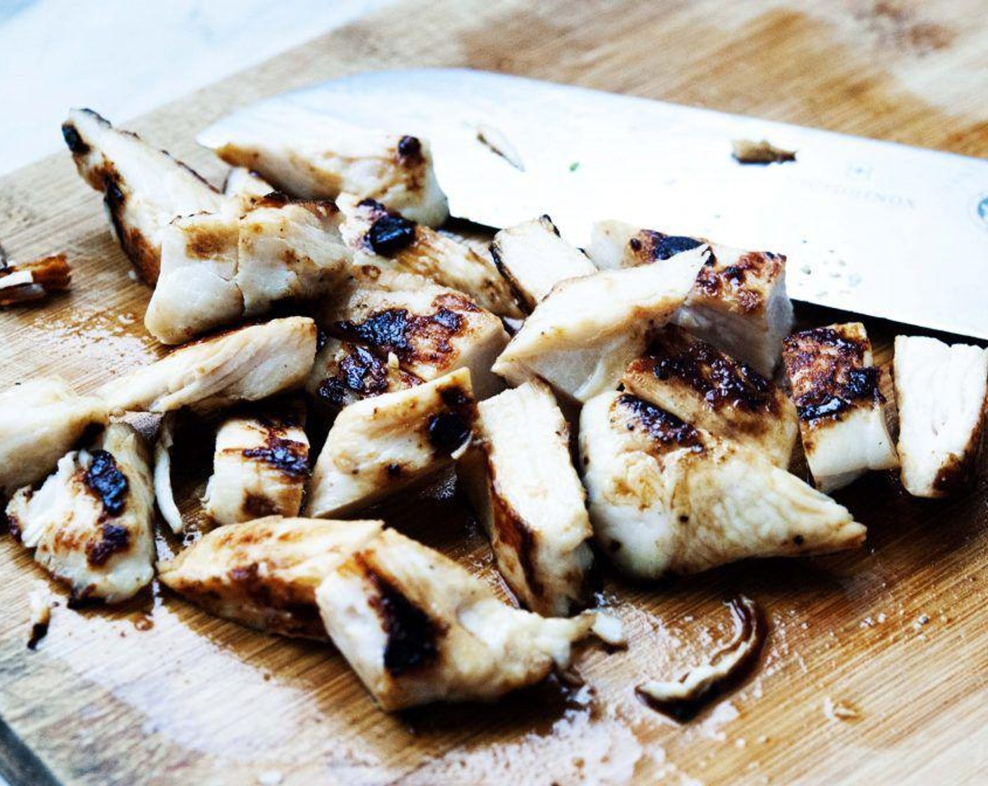 Schritt 5 Hähnchenbrust (250 g) häuten und in Scheiben schneiden. Mit Salz und gemahlenem schwarzen Pfeffer würzen und auf einem heissen Grill oder in einer Pfanne braten. Dann in Würfel schneiden.