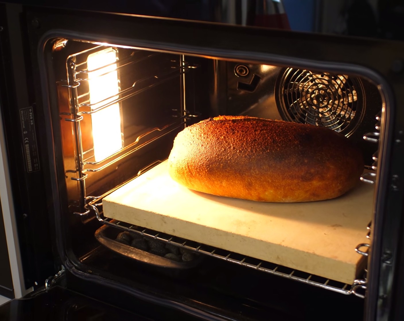 Schritt 11 Nach Ablauf der Zeit, die Schüssel mit dem Wasser aus dem Ofen nehmen, den Dampf ablassen und die Ofentemperatur auf 190° Ober-/Unterhitze reduzieren. Das Brot für weitere 30-35 Minuten knusprig ausbacken.