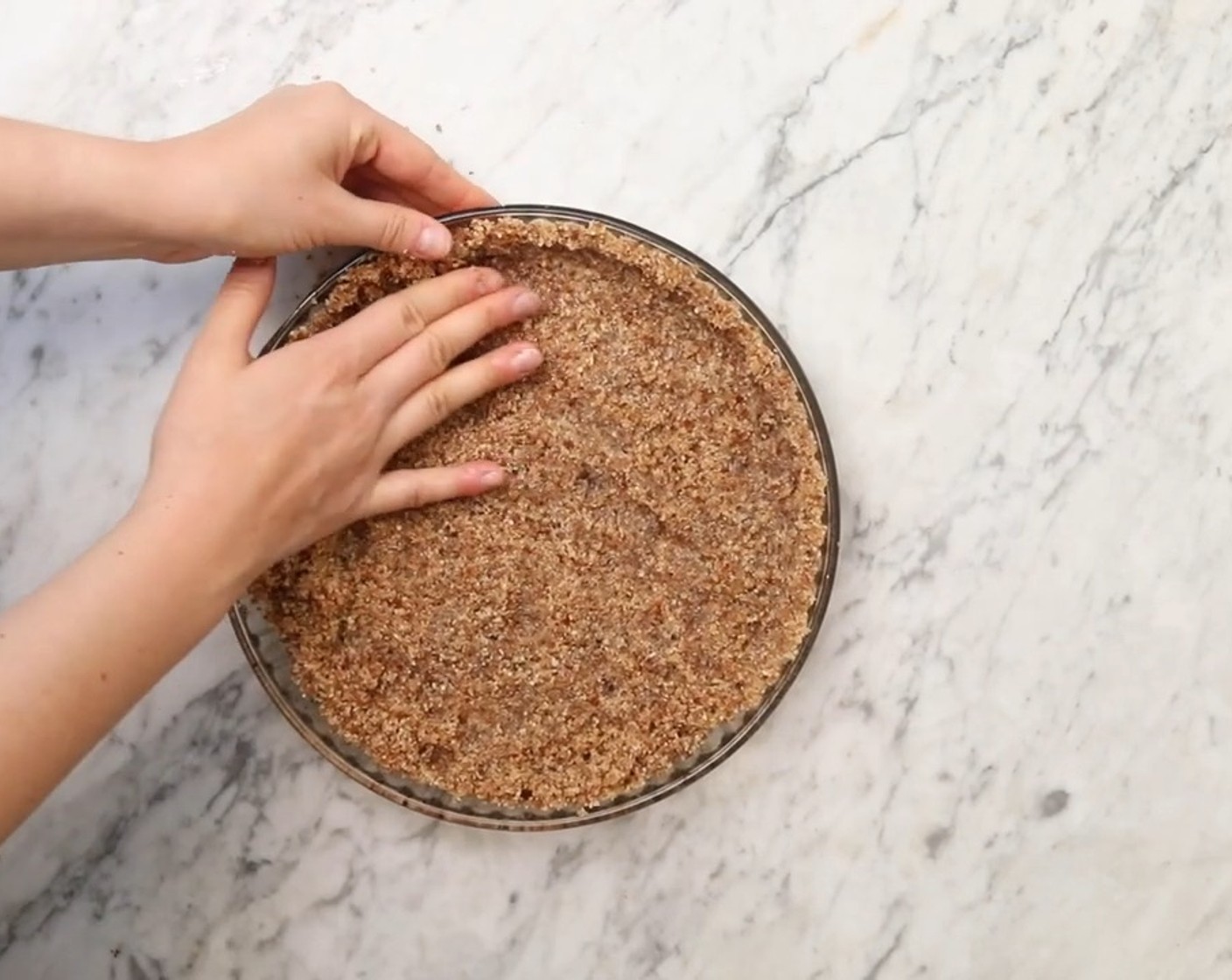 Schritt 2 Kuchenboden: Pekannüsse (120 g), Datteln (120 g), Kokosraspel (70 g) und Ahornsirup (2 Teelöffel) in einen Mixer geben und zu einer dicken, klebrigen Masse verarbeiten. Die Kuchenform mit Öl (nach Bedarf) einfetten, dann die Masse darin verteilen und auf dem Boden und der Seite flack drücken.