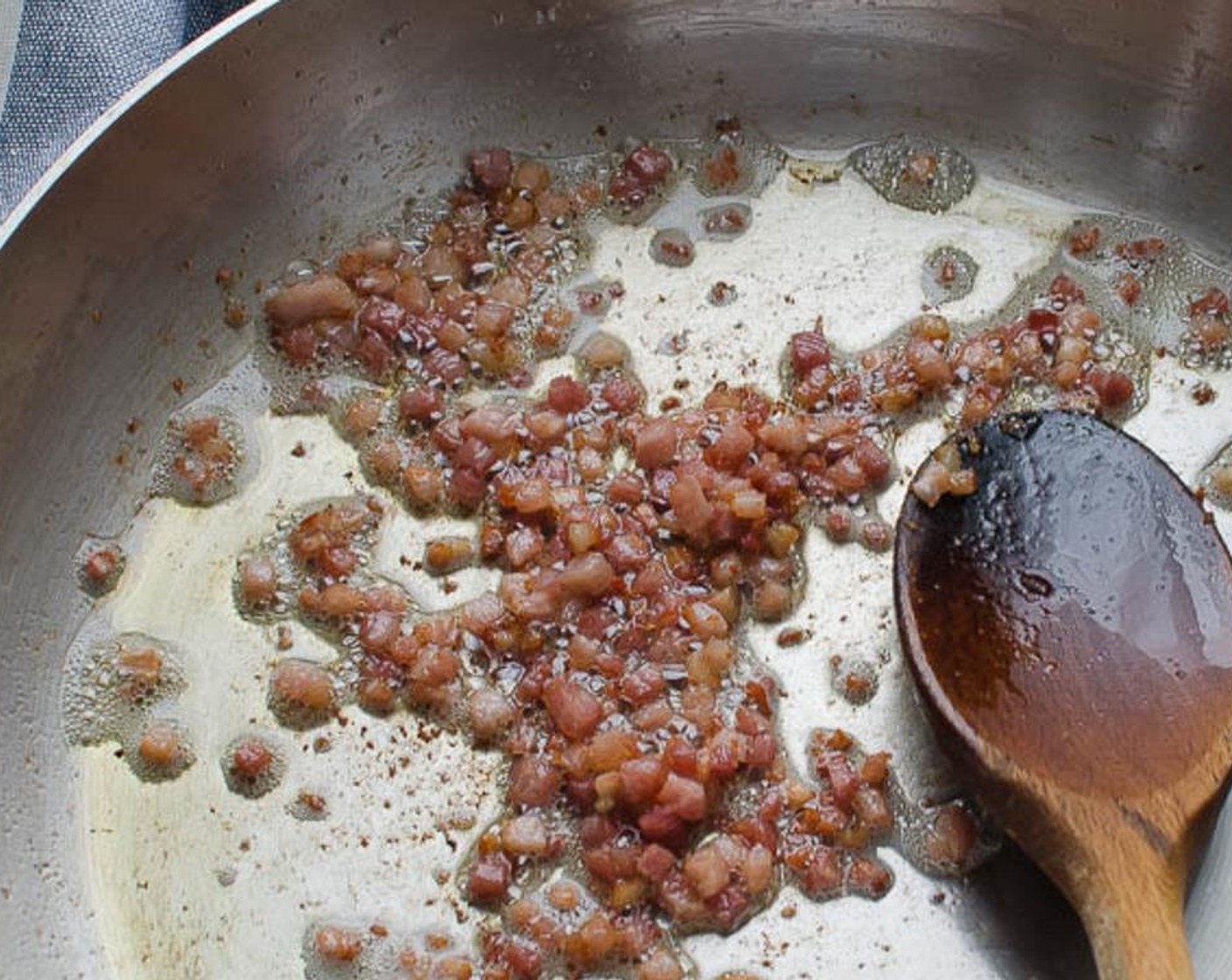 Schritt 2 In einer grossen Pfanne Olivenöl (1 EL) bei mittlerer Hitze erhitzen. Pancetta (4 Esslöffel) hinzufügen und braten, bis er etwas Fett abgegeben hat und knusprig wird. Den Bauchspeck mit einem Schaumlöffel in eine kleine Schüssel geben.