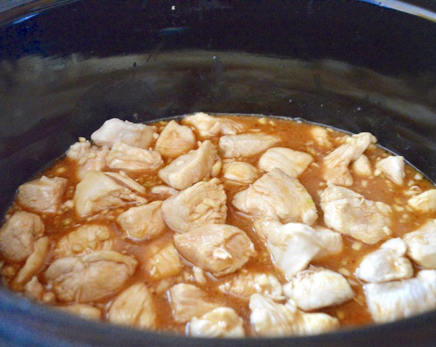 Schritt 3 Die restliche Maizena (2 Esslöffel) mit dem Wasser (120 ml) zu einem Brei verrühren und mit dem Hähnchen in den Kochtopf geben. Gehackten Knoblauch (3 Zehen), Sojasauce (120 ml), Honig (125 g), das restliche Sesamöl (1 EL) und Reisessig (90 ml) hinzufügen. Alles zusammen verrühren und die Hitze auf niedrig stellen. Den Topf verschliessen und alles 3 Stunden kochen lassen.
