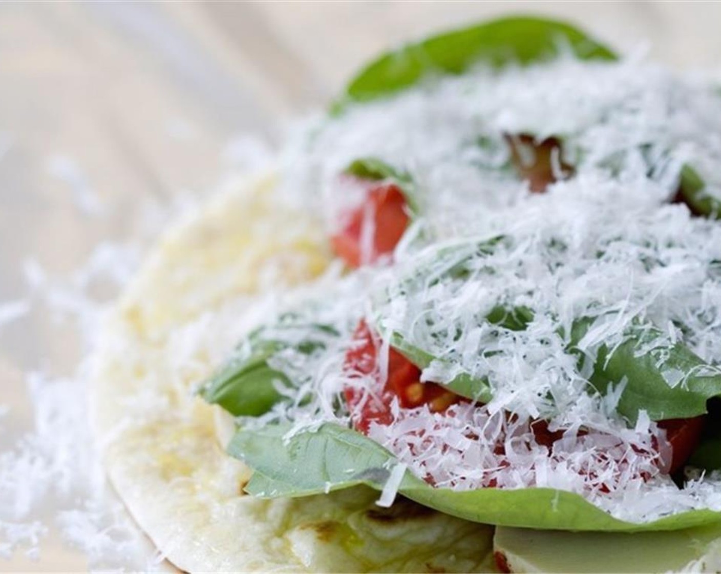 Schritt 3 Auf jedes Fladenbrot Tomatenscheiben (2) legen. Mozzarella (115 g) darauf streuen und Basilikum (1 Bd.) darüber legen. Zum Schluss mit Parmesan (35 g) toppen.