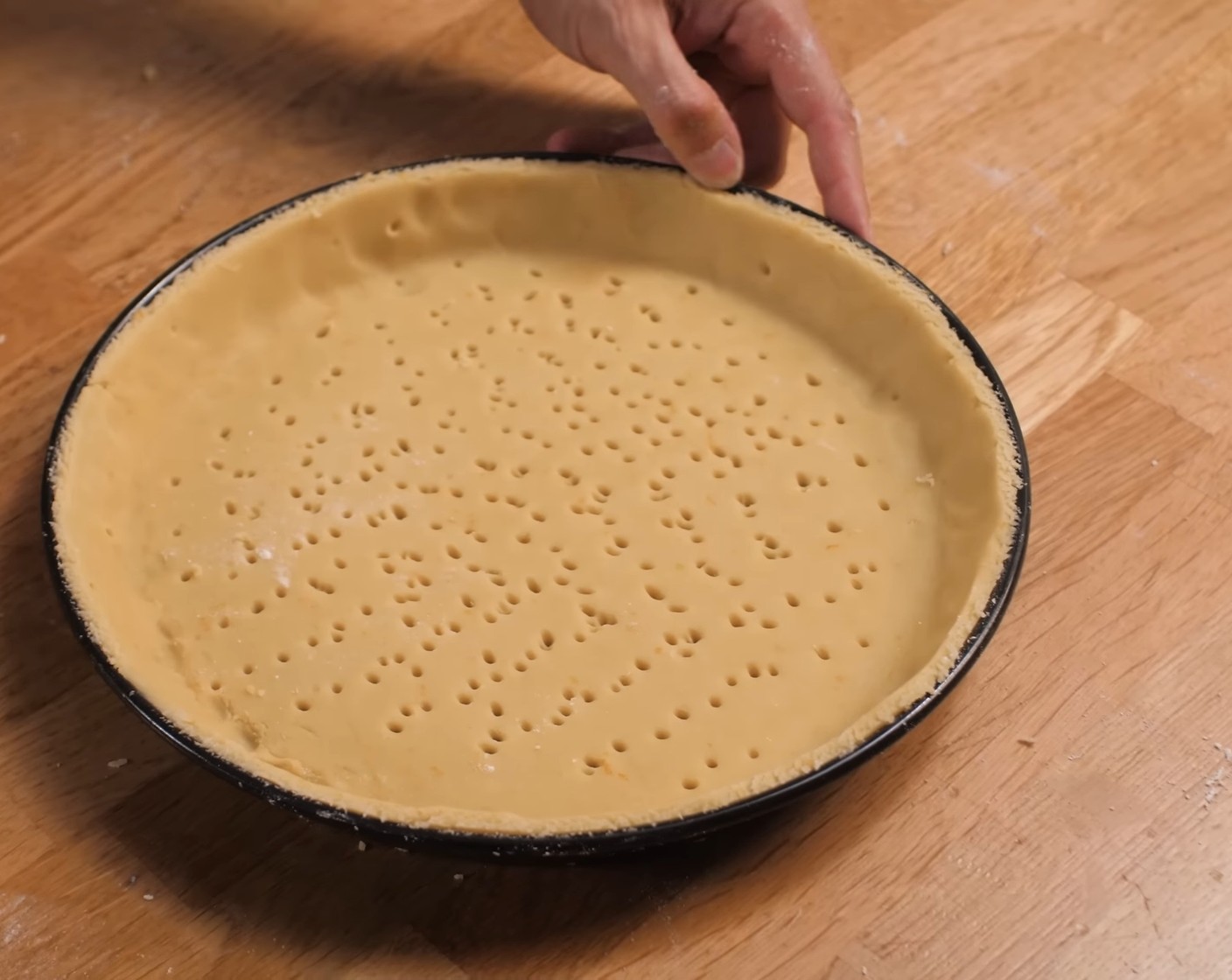 Schritt 10 Anschliessend aus dem Teig einen Kreis mit 23-23.5 cm Durchmesser ausschneiden oder ausstechen.

WICHTIG:
Dieser Kreis muss kleiner sein als der ausgelegte Ring.
Anschliessend diese Teigplatte in den Tartering legen und bündig zu den Kanten drücken.
Den Teigboden und -rand mit Eistreiche bepinseln und den Boden danach nochmals mit einer Gabel stupfen.