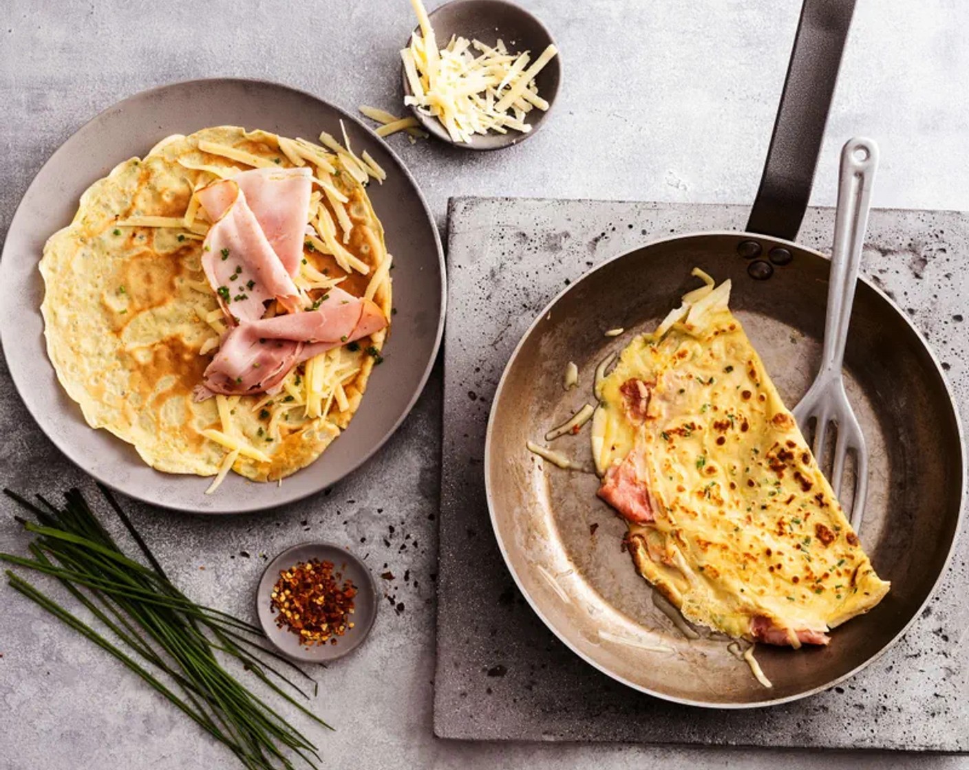 Schritt 6 Emmentaler Käse (250 g) grob reiben. Omeletten nacheinander zur Hälfte mit je 1/8 des Käses und Schinkens (200 g) belegen, zuklappen und in der heissen Bratpfanne nochmals kurz erhitzen, bis der Käse geschmolzen ist.