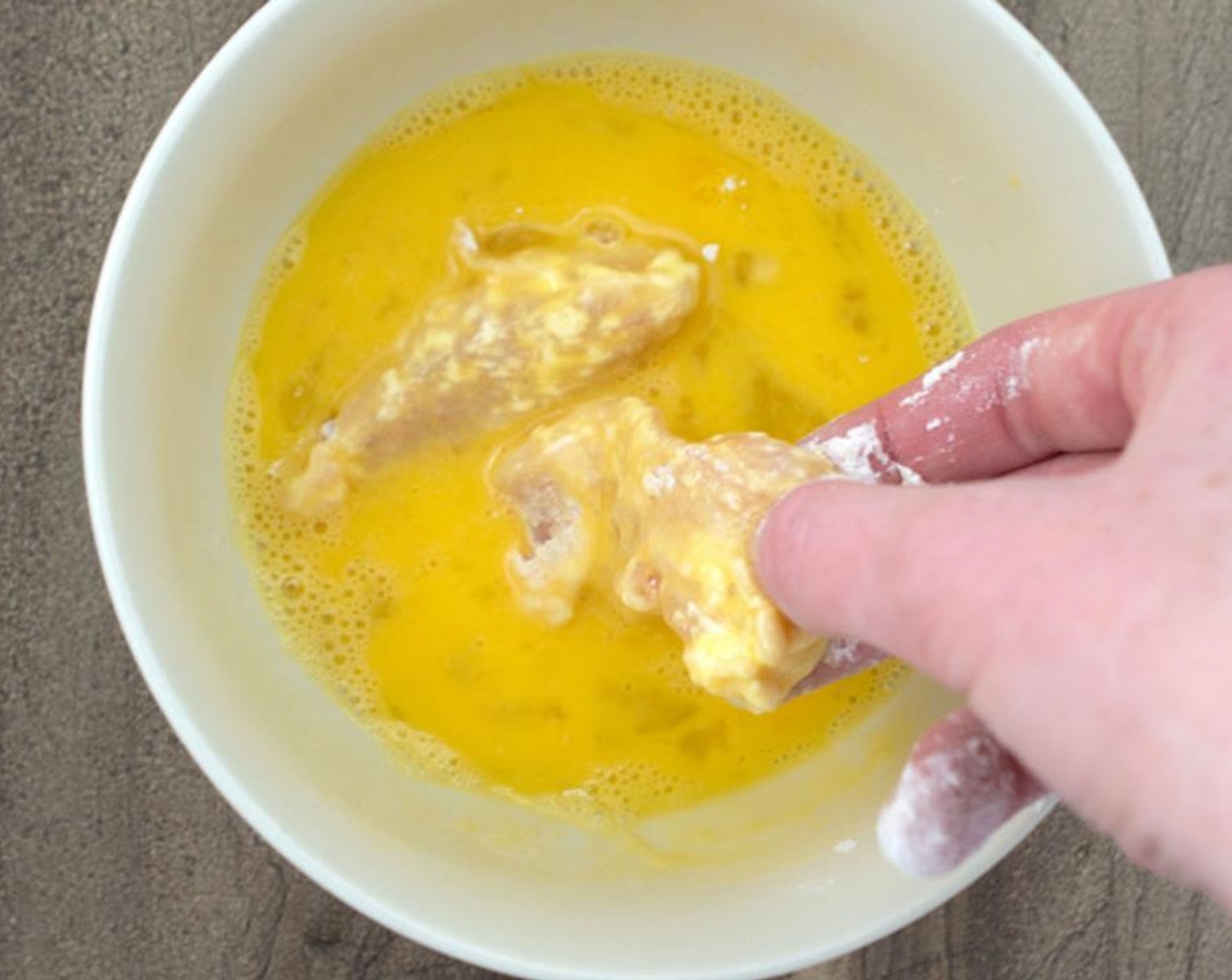 Schritt 5 Die bemehlten Hähnchenteile in die Eimischung legen. Darauf achten, das überschüssige Ei zu entfernen.