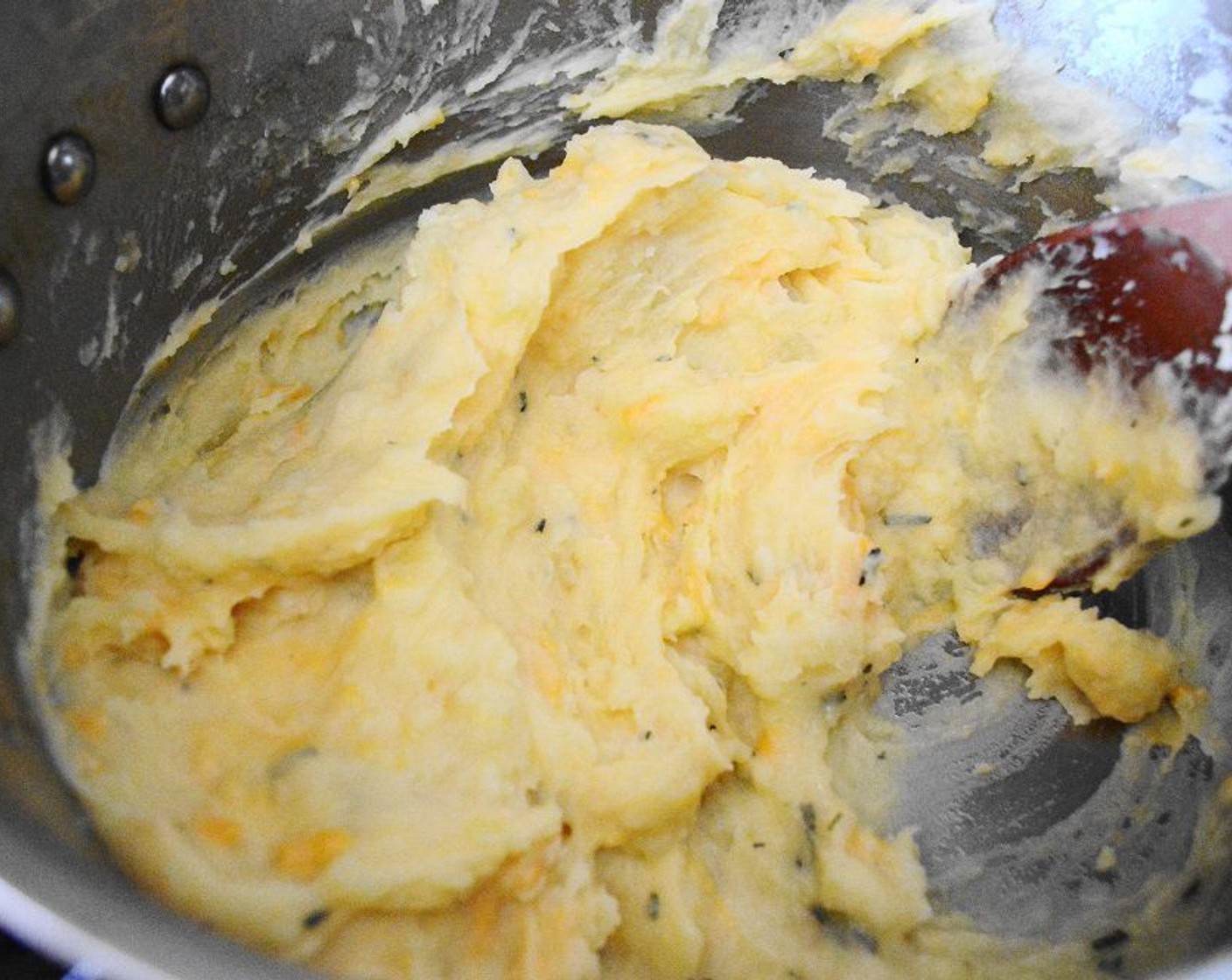 Schritt 8 Die Kartoffeln abgiessen und in den Topf zurückgeben, in dem sie gekocht wurden. Die heisse Buttermischung über die Kartoffeln giessen. Dann Cheddar (115 g) und Salz (1 Pr.) hinzufügen. Die Mischung pürieren und 1 Minute lang abkühlen lassen.