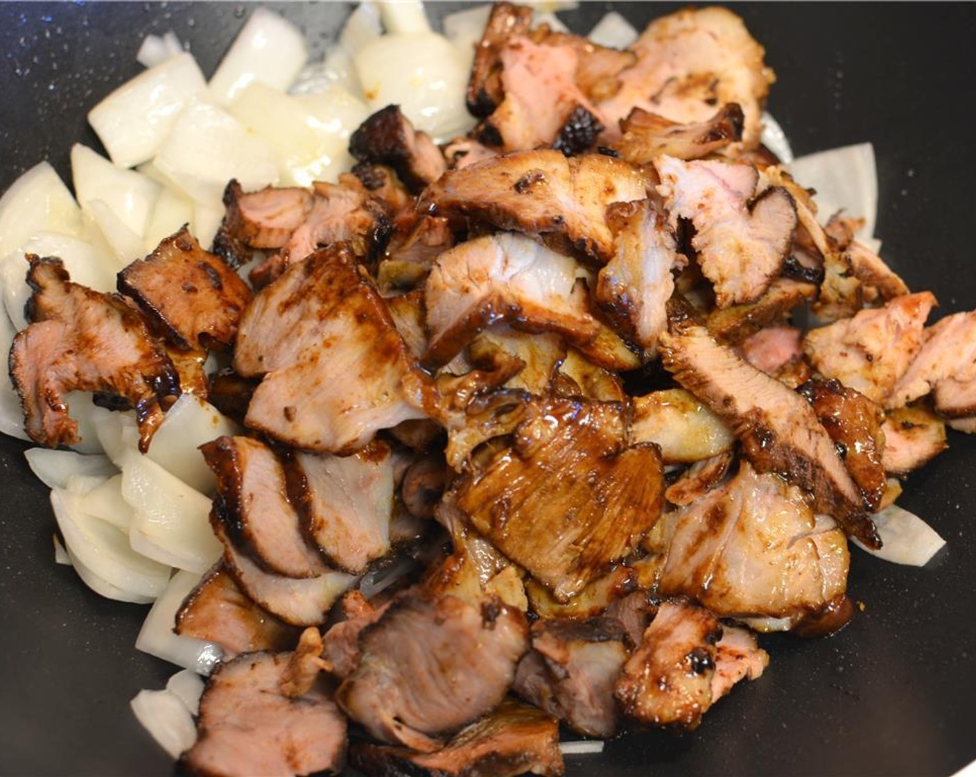 Schritt 10 Das in Scheiben geschnittene Schweinefleisch dazugeben und zusammen den Zwiebeln gut durchschwenken.