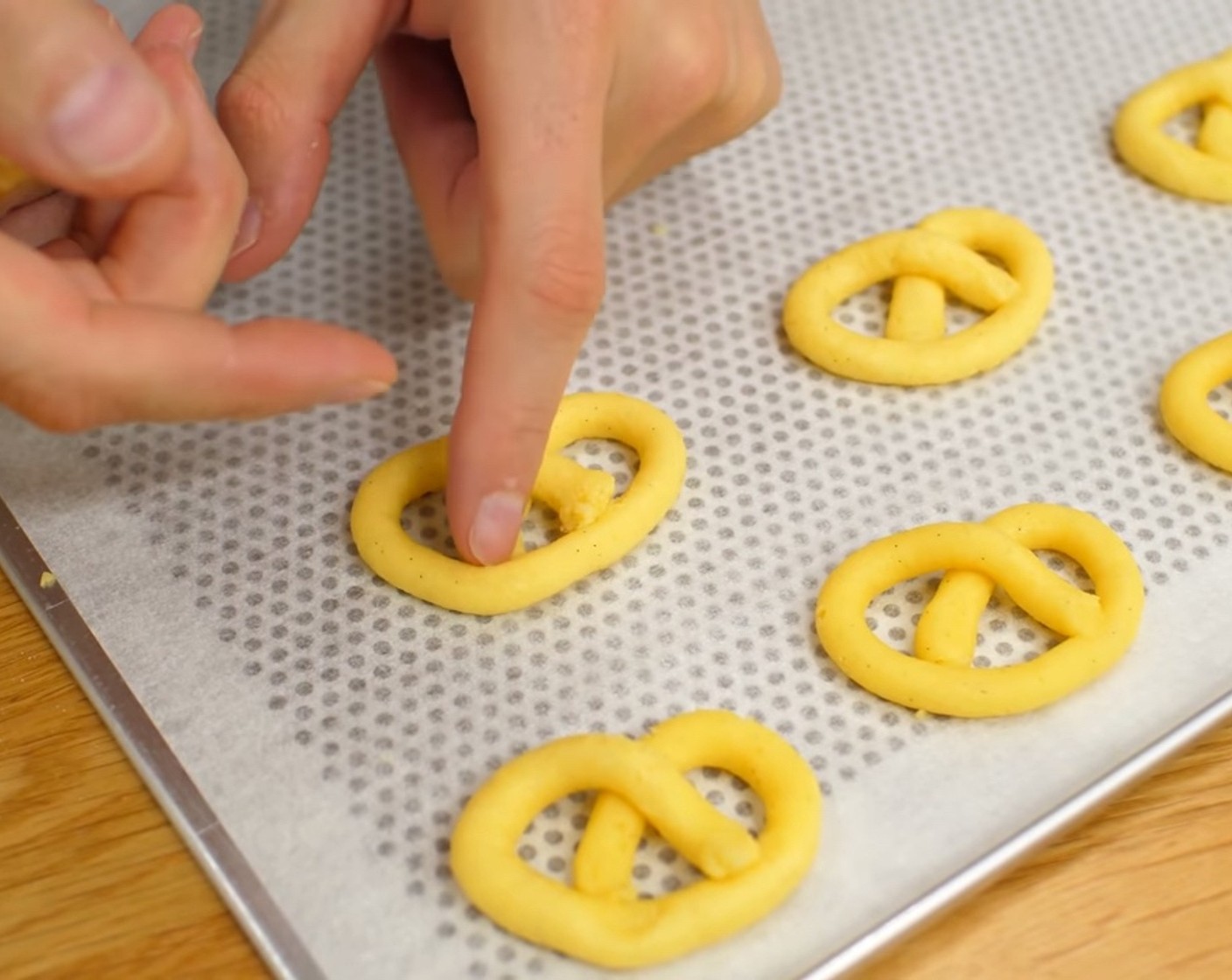 Schritt 5 Mit der Masse gleichmässige Brezel auf ein mit Backpapier belegtes Blech spritzen. Da die Masse eher fest ist, kann man die Form der Brezel problemlos mit den Fingern korrigieren.