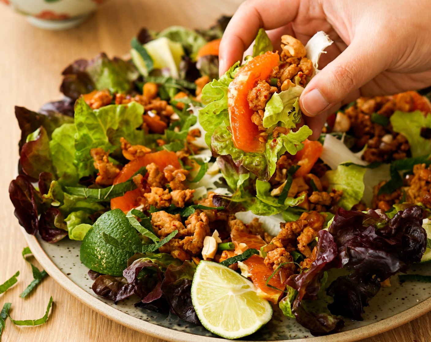 Schritt 4 Salatblätter (nach Bedarf) auf einer Servierplatte anrichten. Jedes Salatblatt mit einem gehäuften Löffel Larb und mit Orangenspalte (1) füllen. Mit Minze (1 Handvoll) garnieren und mit zusätzlichen Limettensaft geniessen!
