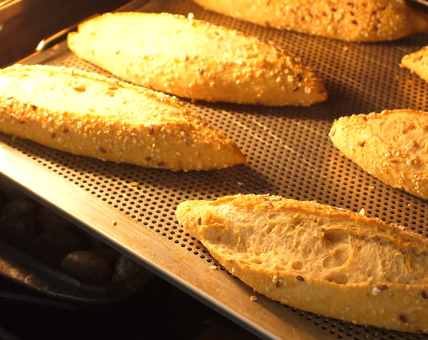 Schritt 16 Nach 20 Minuten die Schüssel mit dem Wasser und das obere leere Blech aus dem Ofen nehmen, die Ofentemperatur auf 215 °C reduzieren und die Brote für weitere 10-15 Minuten knusprig ausbacken.