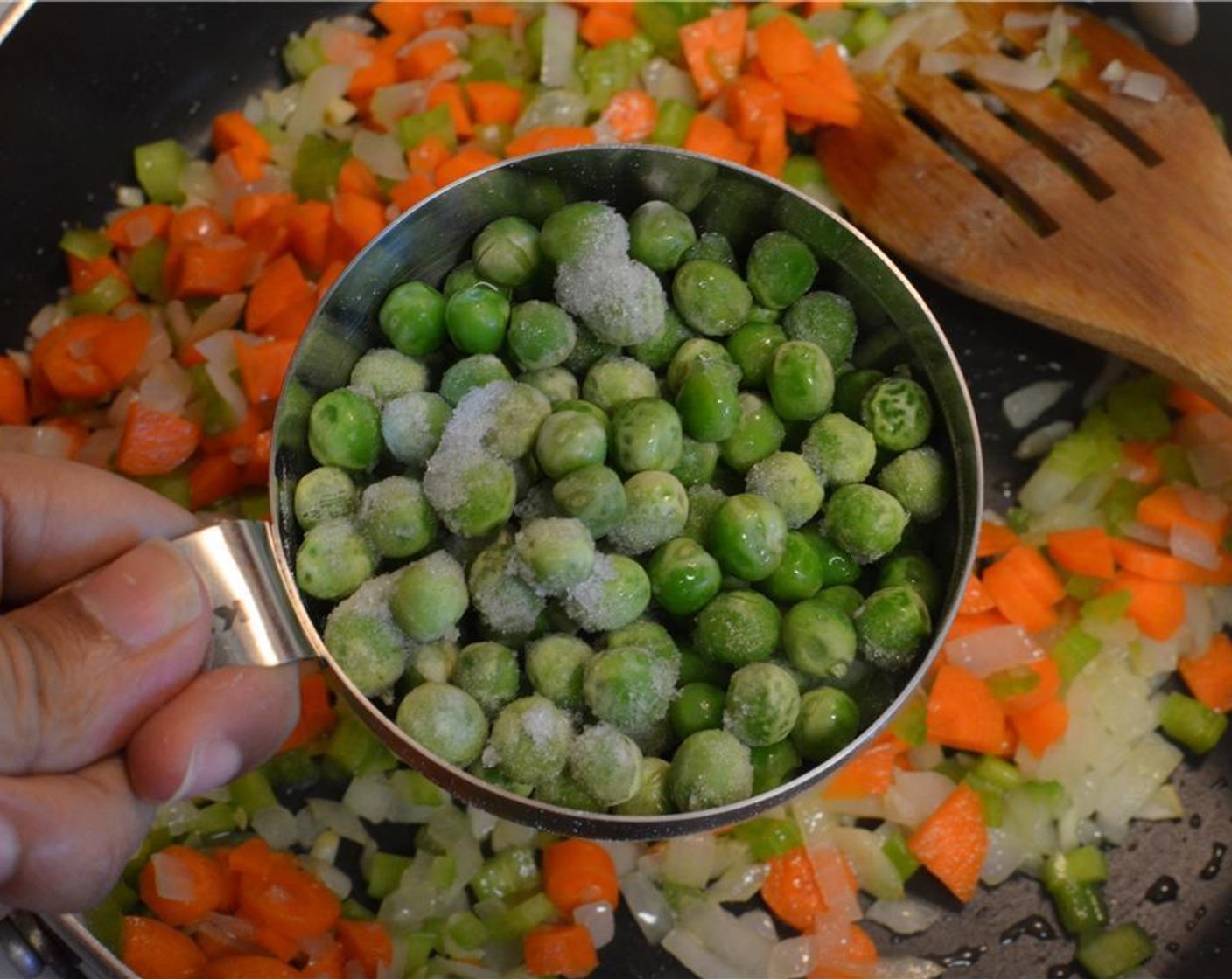 Schritt 4 Gewürfelte Karotten (2), gewürfelten Sellerie (2 Stängel) und Erbsen (80 g) in die Pfanne geben. Alles gut umrühren.