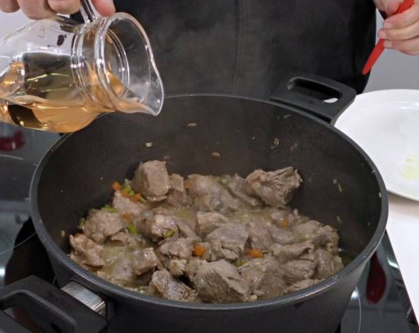 Schritt 3 Sobald das Lammfleisch gebräunt ist, Weisswein (480 ml), Tomatensauce (95 g) und so viel Wasser (wenig) hinzugeben, dass das Fleisch bedeckt ist.