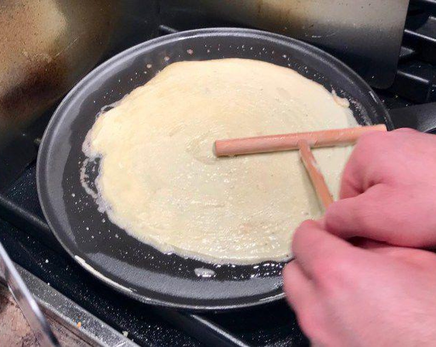 Schritt 3 Eine Crêpe-Pfanne bei mittlerer Hitze mit Butter einfetten. Eine Portion Teig in die Mitte der Pfanne giessen und dann mit dem Crêpe-Paddel in einem grossen, gleichmässigen Kreis verteilen. Dafür einfach 360° drehen.
