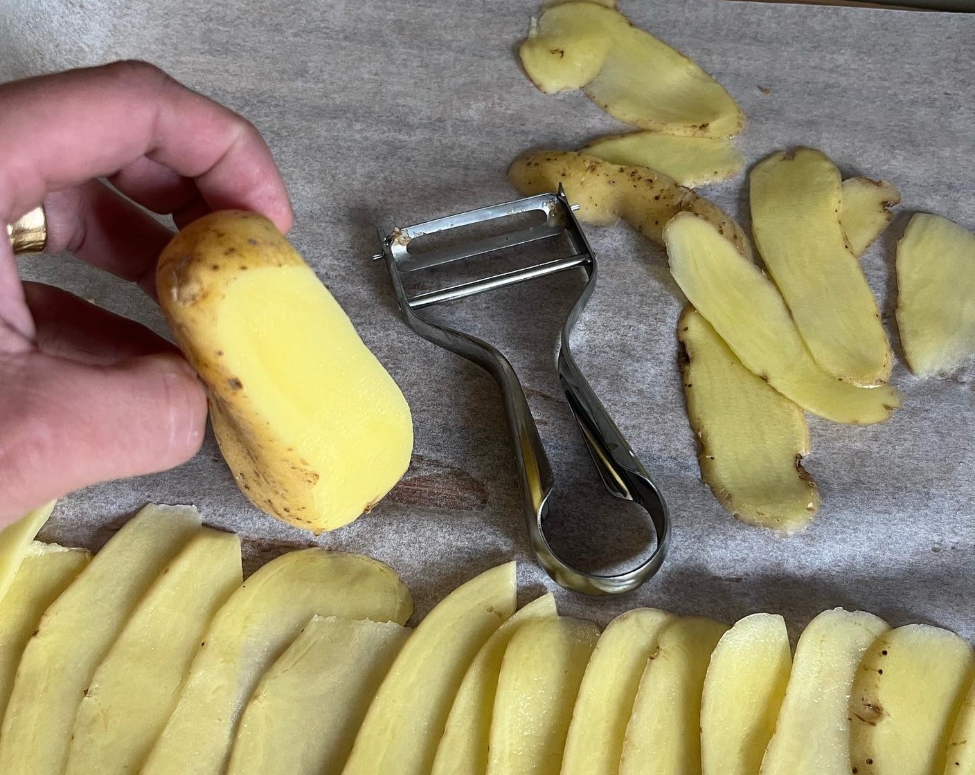 Schritt 1 Kartoffeln (3) mit dem Sparschäler in dünne Scheiben raffeln, auf ein Backpapier leicht überlappend, verteilen.