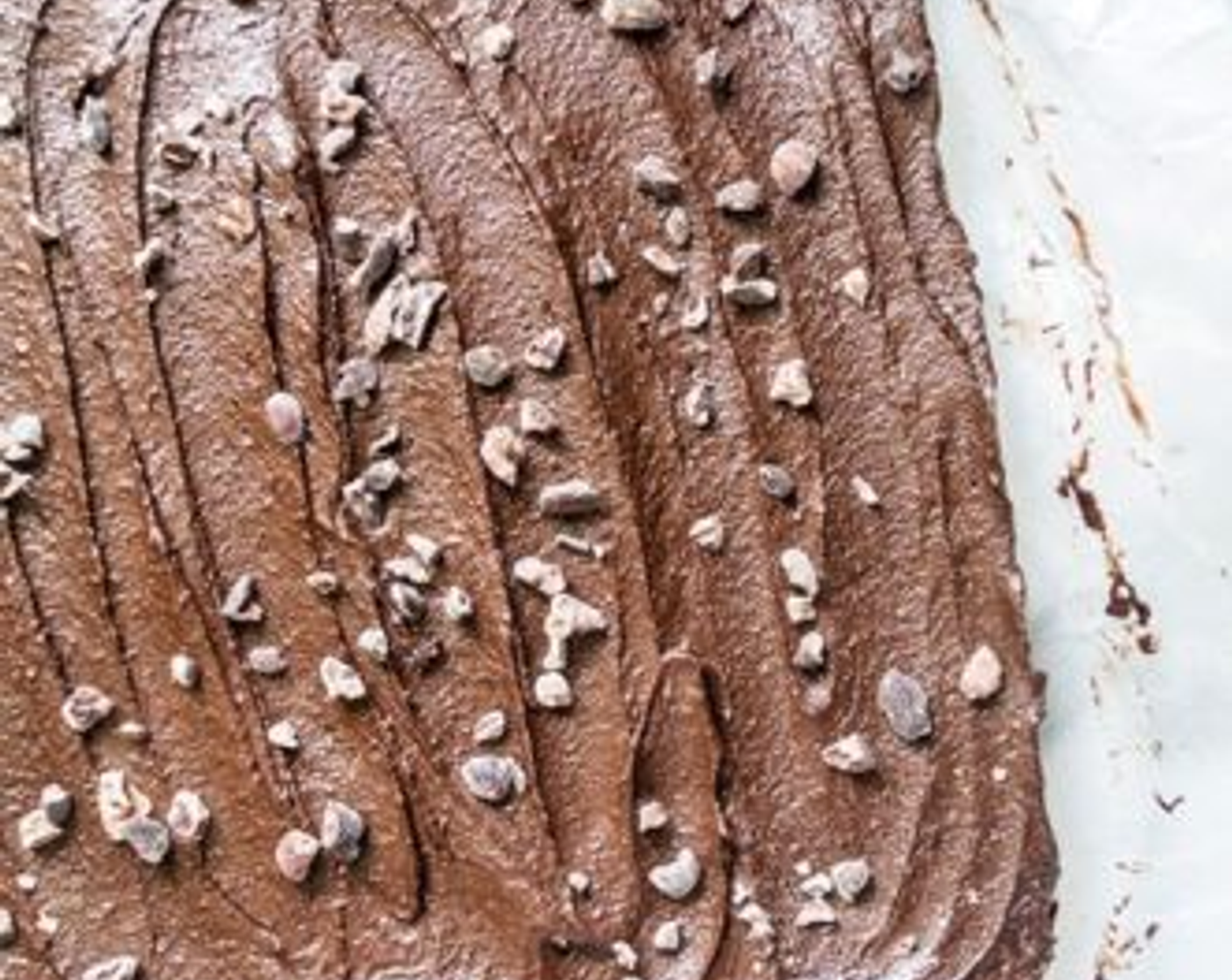 Schritt 8 Den Zuckerguss auf den gepressten Brownies verteilen, mit Kakaonibs (2 Teelöffel) bestreuen und die Form für etwa 30 Minuten in den Gefrierschrank stellen.