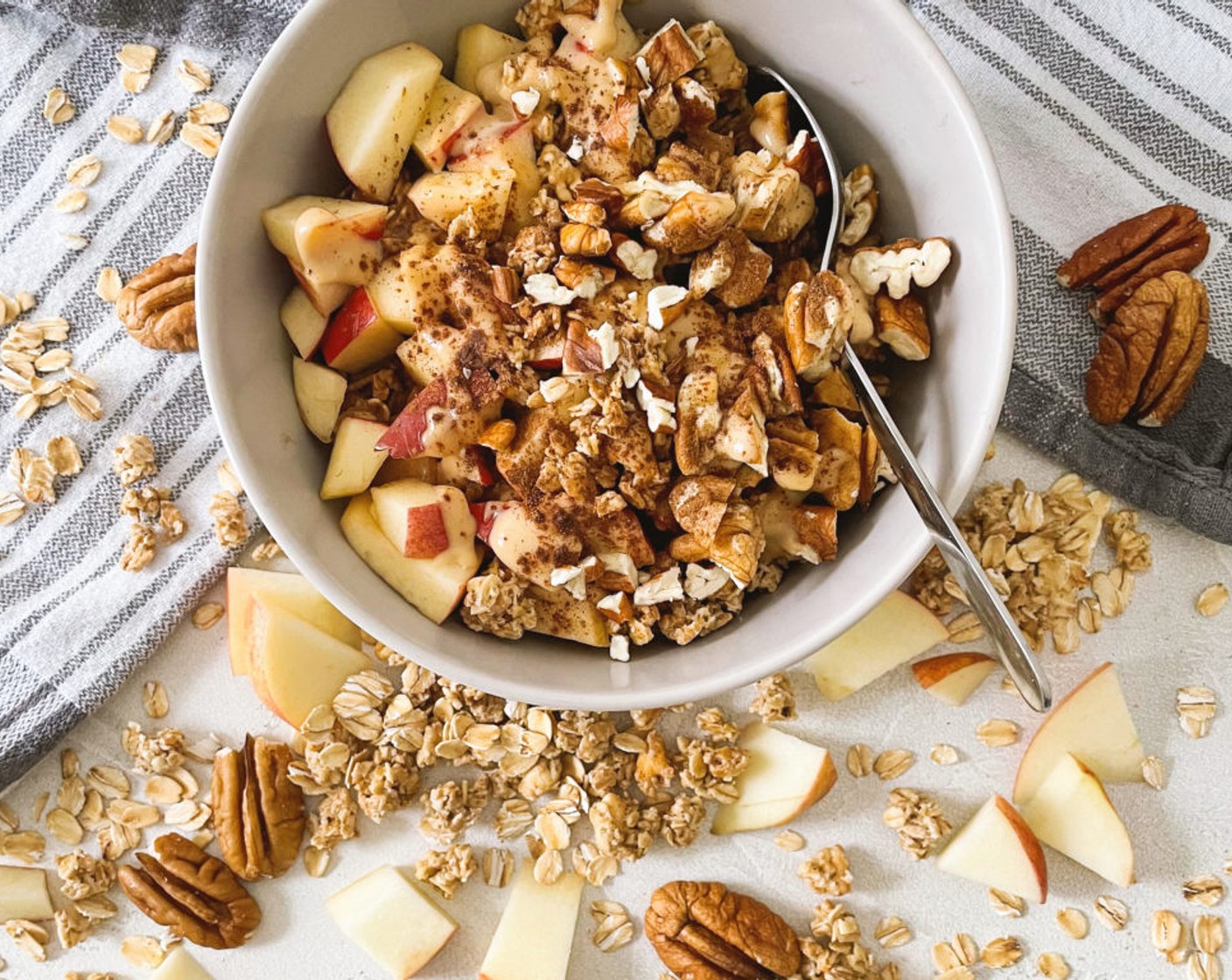 Schritt 4 Den Mix in eine Schüssel geben, die beiseitegelegten Apfelstückchen zusammen mit den Pekannüssen (1 Handvoll) und dem Granola (2 Esslöffel) darübergeben. Zum Schluss das Ganze mit Mandelmus (1 EL) und Ahornsirup (1 TL) beträufeln.