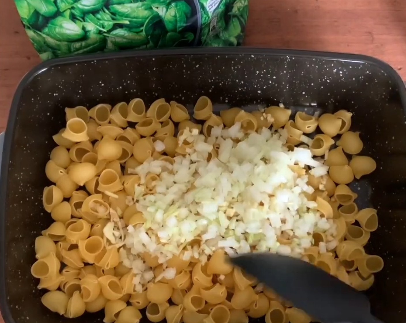 Schritt 1 Pasta (350 g) und Rapsöl (2 Esslöffel) in einen Bräter geben. Zwiebel (1) und Knoblauch (1 Zehe) schälen und klein hacken, ebenfalls beigeben.