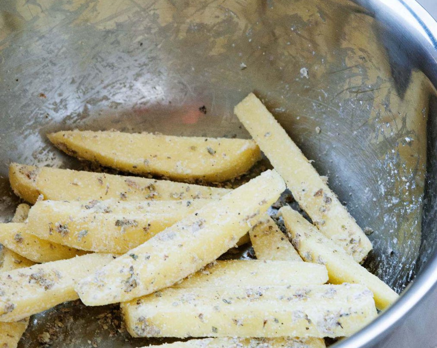 Schritt 4 Für die Kartoffelecken: Kartoffeln (2) waschen, schälen und schneiden. Mit Kräutern (wenig), geschmolzenem Kokosöl (2 Esslöffel), Speisestärke (2 Esslöffel), Salz (wenig) und Pfeffer (wenig) mischen.