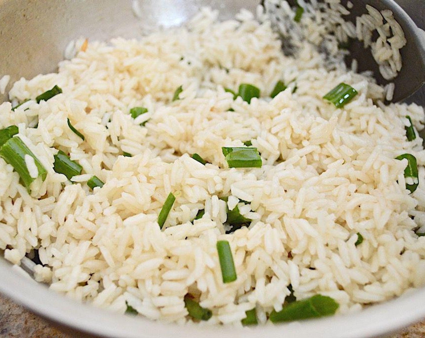 Schritt 4 Der Reis benötigt etwa 15 bis 20 Minuten, bis er weich ist. Wenn er fertig ist, geschnittene Bundzwiebeln (7 Teelöffel) einrühren und im heissen Reis ziehen lassen.