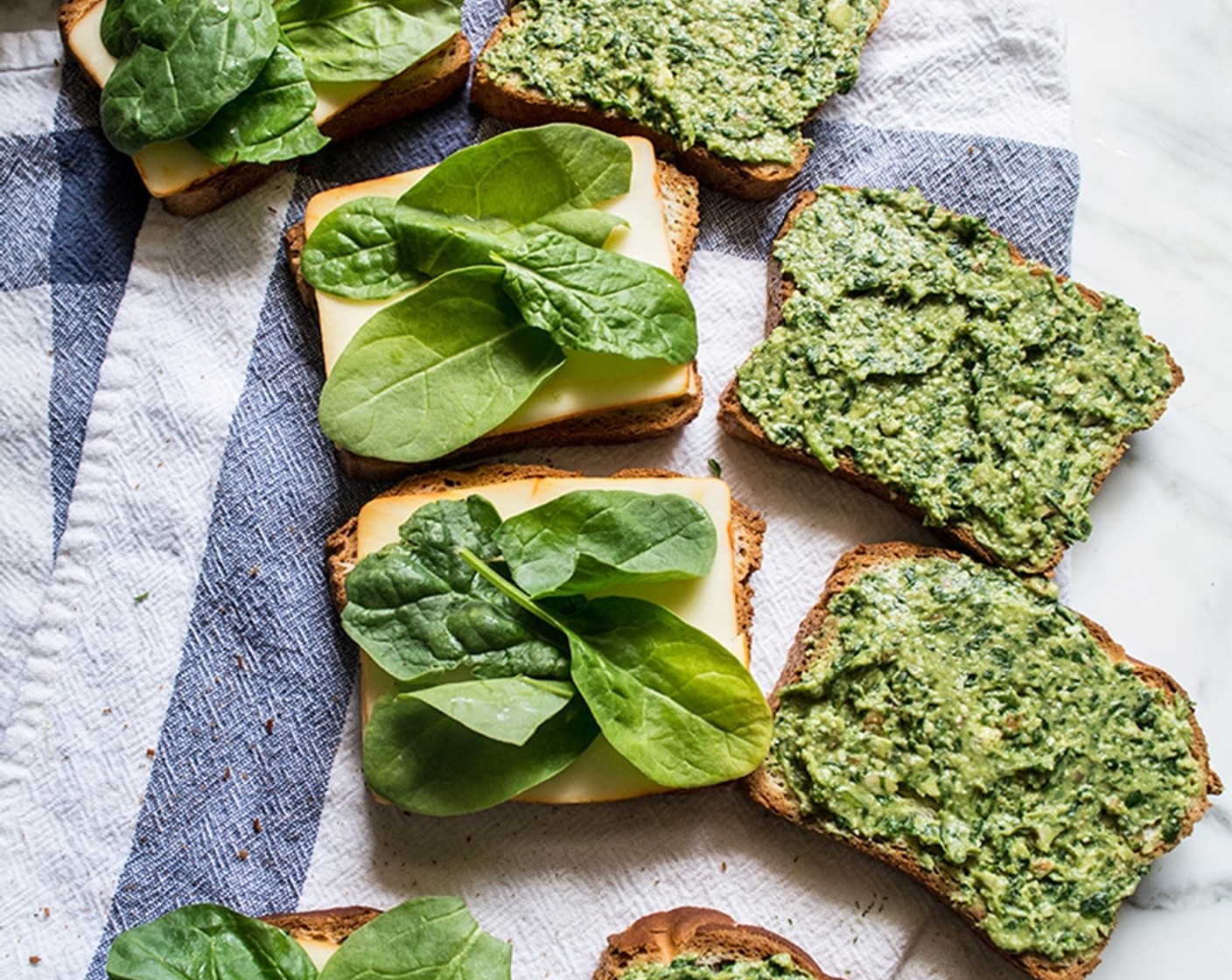 Schritt 4 Brot (8 Scheiben) mit Spinat-Pesto bestreichen, mit zusätzlichen Spinatblättern (wenig) belegen und mit Ziegenkäse (wenig) bestreuen. Die Hälfte der Brotscheiben mit Käse (4 Scheiben) belegen und mit der anderen Hälfte zusammen klappen. Vorgang wiederholen, um die anderen Sandwiches fertigzustellen.