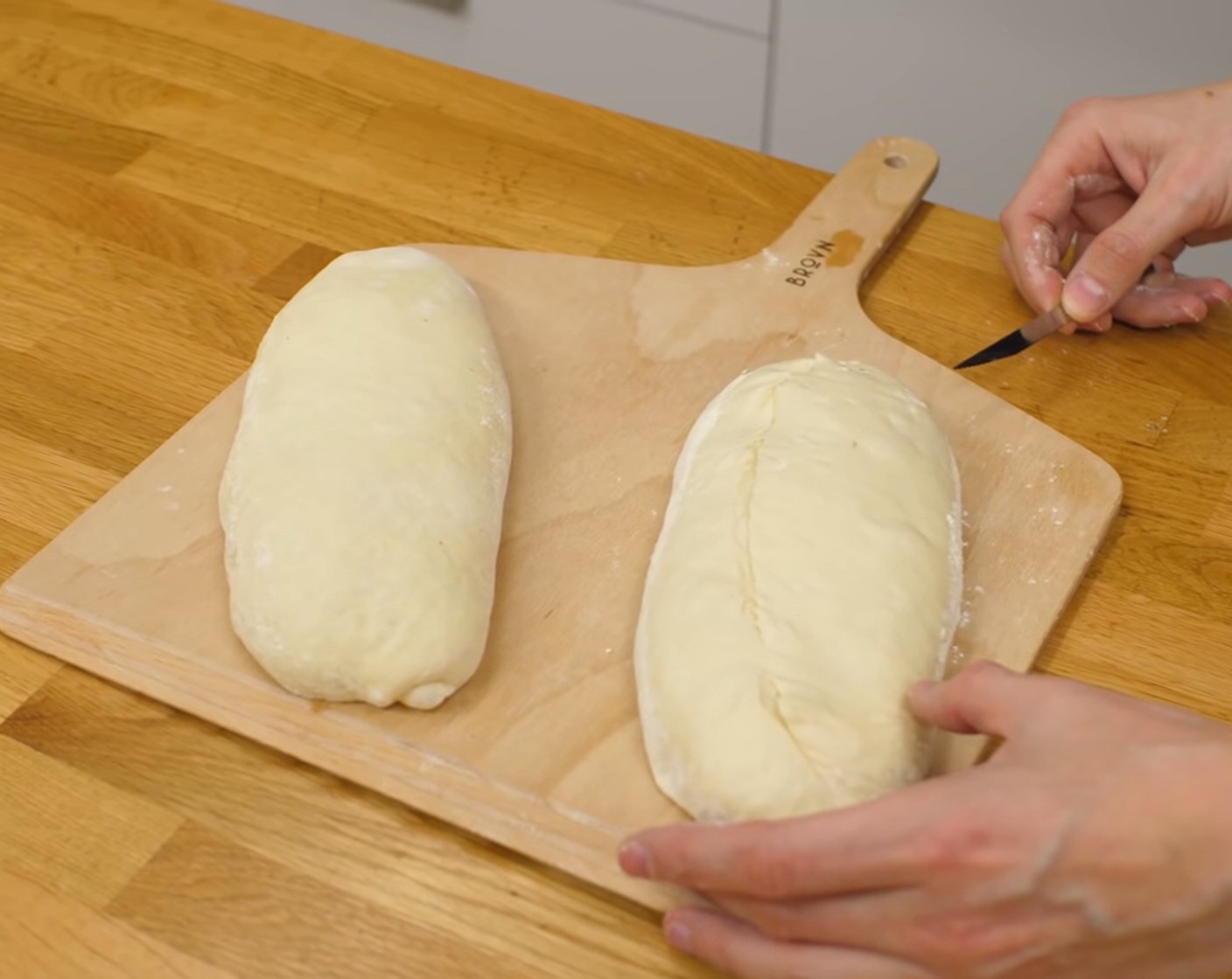 Schritt 12 Nach der Gärzeit, die Teiglinge auf eine bemehlte Brotschaufel geben und die Oberfläche mit einem scharfen Messer im 45-Grad-Winkel 1-mal länglich einschneiden. Dabei die Klinge NICHT gerade sondern leicht gebogen führen.