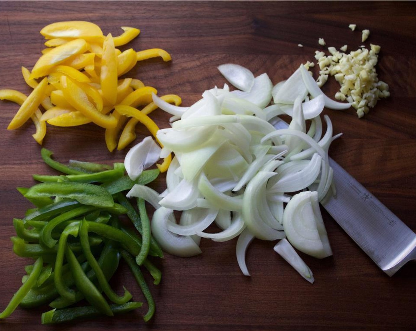Schritt 3 Zwiebel (1), gelbe Peperoni (1) und grüne Peperoni (1) in Streifen (Julienne) schneiden. Knoblauch (5 Zehen) schälen und fein hacken.