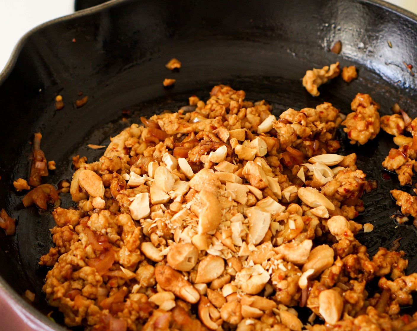 Schritt 1 Olivenöl (2 Esslöffel) in einer Pfanne auf mittlerer bis hoher Stufe erhitzen. Das Hackfleisch (225 g) in die Pfanne geben und mit Chiliflocken (1 TL), Kosher Salz (nach Bedarf), Zucker (1 TL) und Fischsauce (1 EL) würzen. Das Hühnerfleisch mit einem Spatel in kleine Krümel zerteilen und durchschwenken, um es gleichmässig mit den Gewürzen zu bedecken. 5 Minuten weiter garen, bis das Huhn weitgehend durchgegart ist.