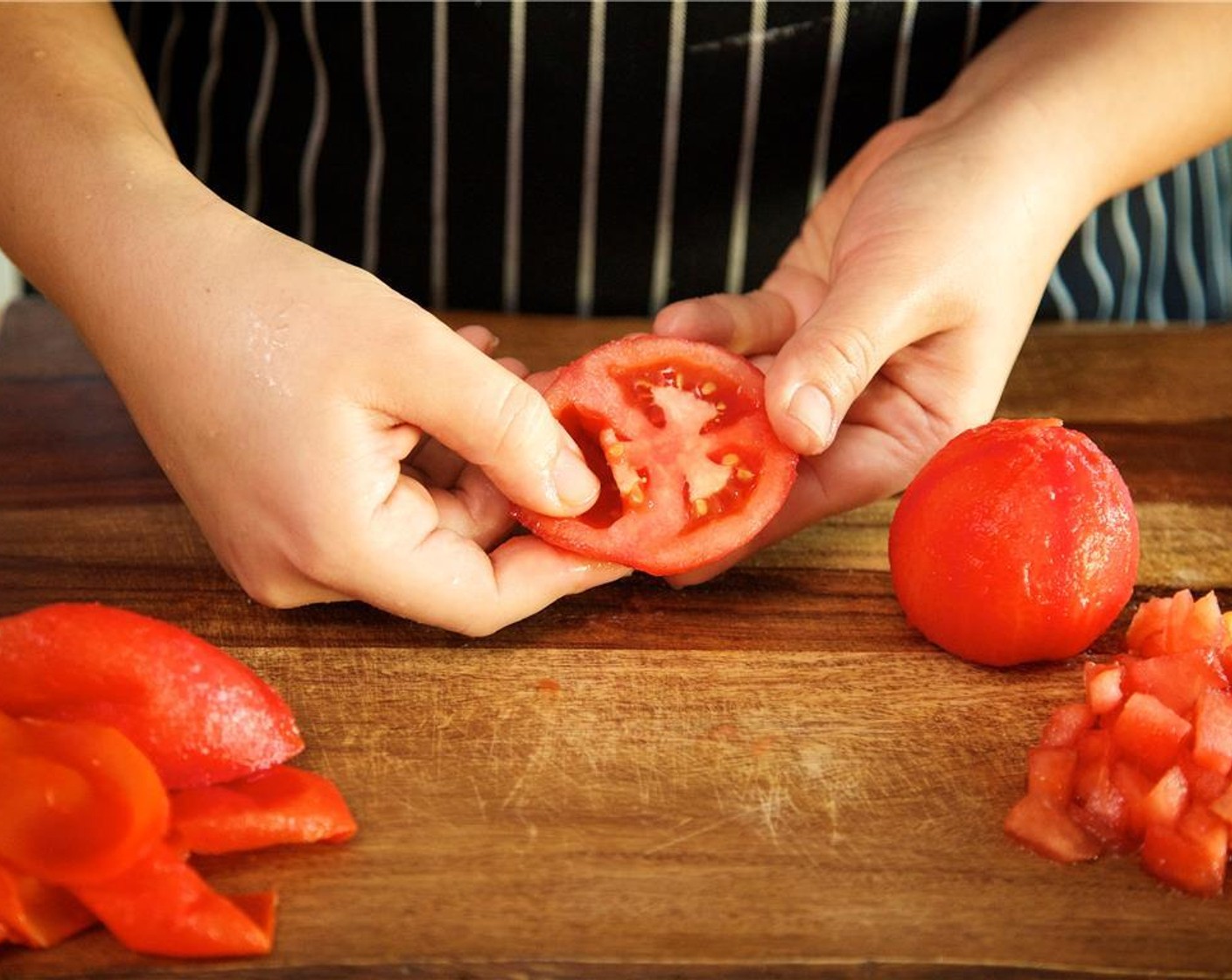 Schritt 10 Wenn die Tomaten abgekühlt sind, die Haut von den Tomaten abziehen und wegwerfen. Jede Tomate horizontal in zwei Hälften schneiden und die Samen und das innere Fruchtfleisch entfernen.