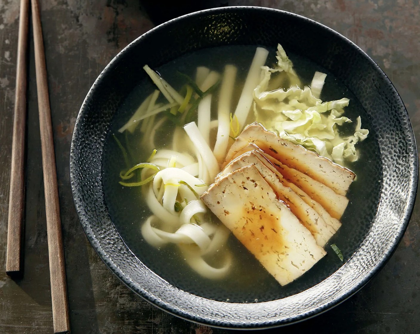 Schritt 3 Chinakohl (60 g) längs halbieren und quer in feine Streifen schneiden. Tofu (200 g) in dünne Streifen schneiden und mit dem Chinakohl zur Bouillon geben. Ca. 2 Minuten heiss werden lassen. Mit Reisessig (2 Esslöffel) und Sojasauce (1 EL) abschmecken und anrichten.