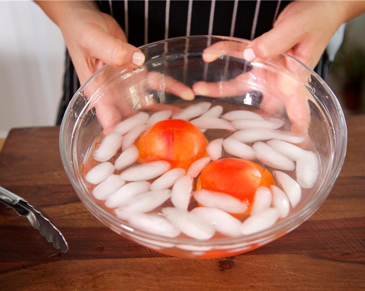 Schritt 9 Ein etwa 5 Zentimeter grosses X am mittleren unteren Ende der Tomaten (2) einschneiden. Die Tomaten für 30 Sekunden in das kochende Wasser legen und danach in das Eiswasser geben.