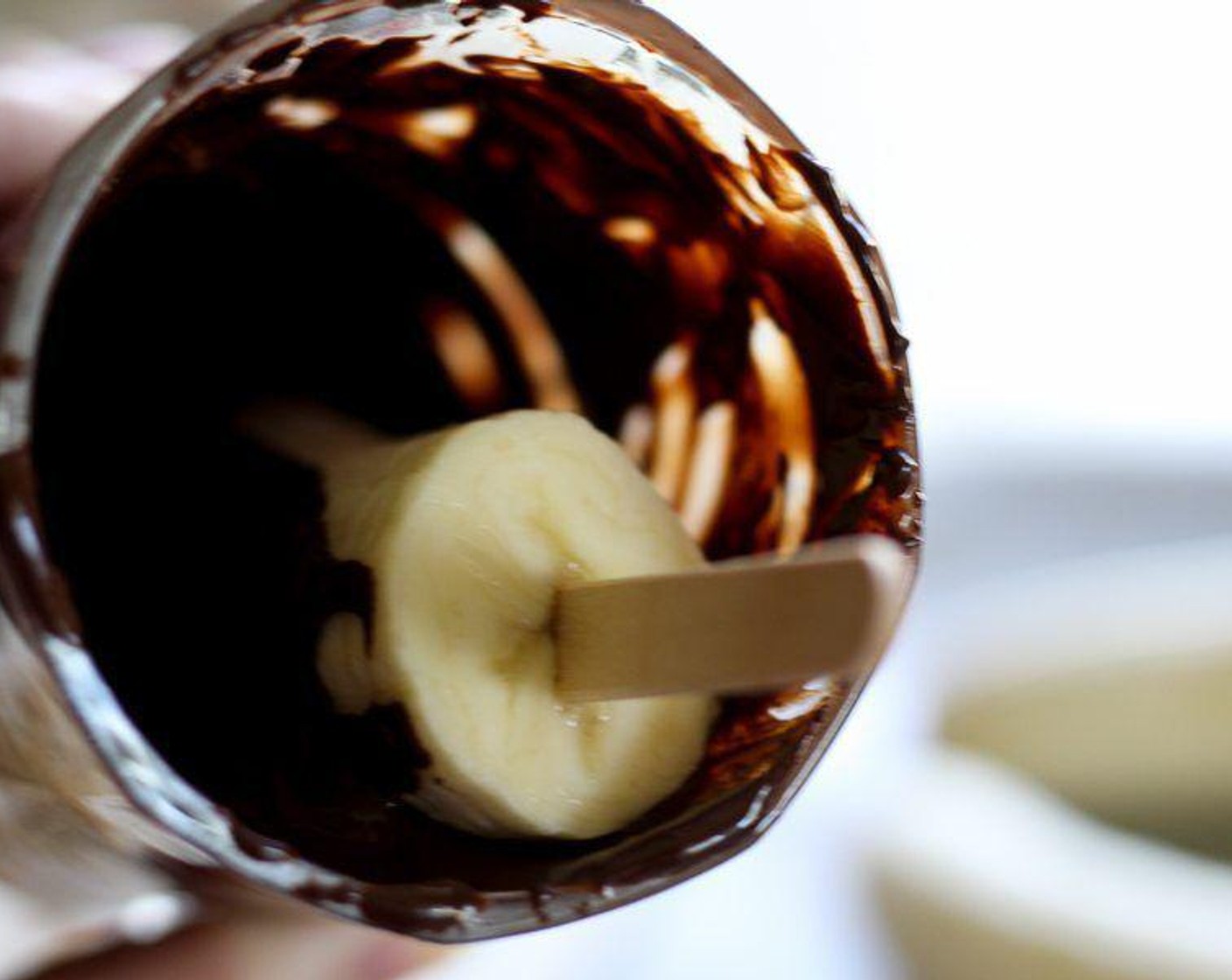Schritt 4 Den Bananen-Pop vorsichtig in der geschmolzenen Schokolade drehen, bis alles gleichmässig überzogen ist.