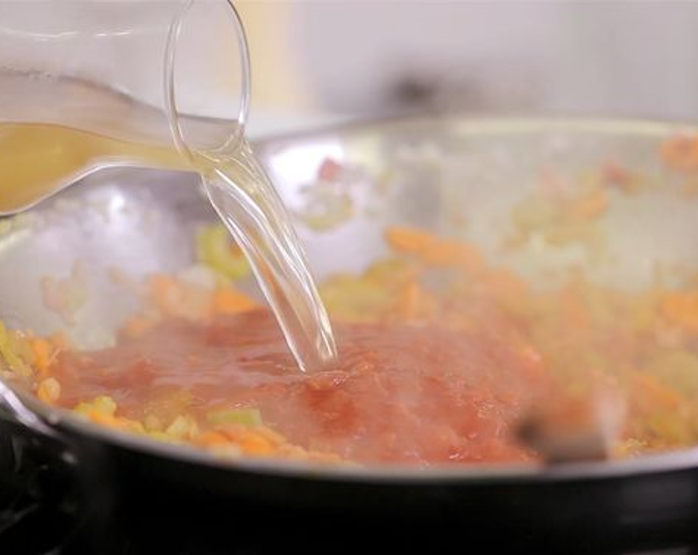 Schritt 3 Anschliessend das Olivenöl (1 EL) im Wok erhitzen, den Speck zugeben und anschwitzen. Danach die Karotten, den Stangensellerie, Knoblauch und die Zwiebeln in den Wok geben und anbraten. Nun die Tomaten Passata (1 EL) hinzufügen und kurz mit anbraten. Als nächstes die Kartoffel- und Pelati Pomodoro (400 g) sowie den restlichen Petersilienbund und die Bouillon (1.5 L) zugeben. Das Ganze zum Kochen bringen.