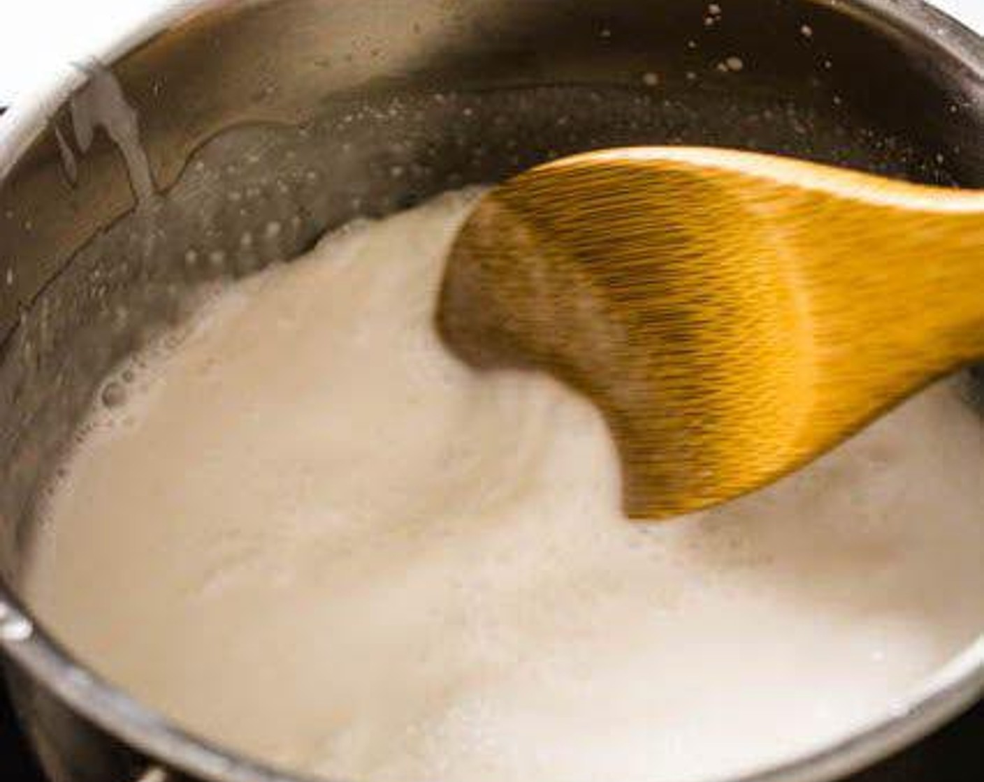 Schritt 3 In einem kleinen Topf Kokosmilch (240 ml) bei mittlerer Hitze erhitzen. Sobald sie zu kochen beginnt, Zucker (8 Teelöffel) und Salz (1 Pr.) hinzufügen. Umrühren, bis sich der Zucker und das Salz aufgelöst haben. Etwa 1/4 Tasse der Kokosnussmilchmischung zum späteren Servieren beiseitestellen.