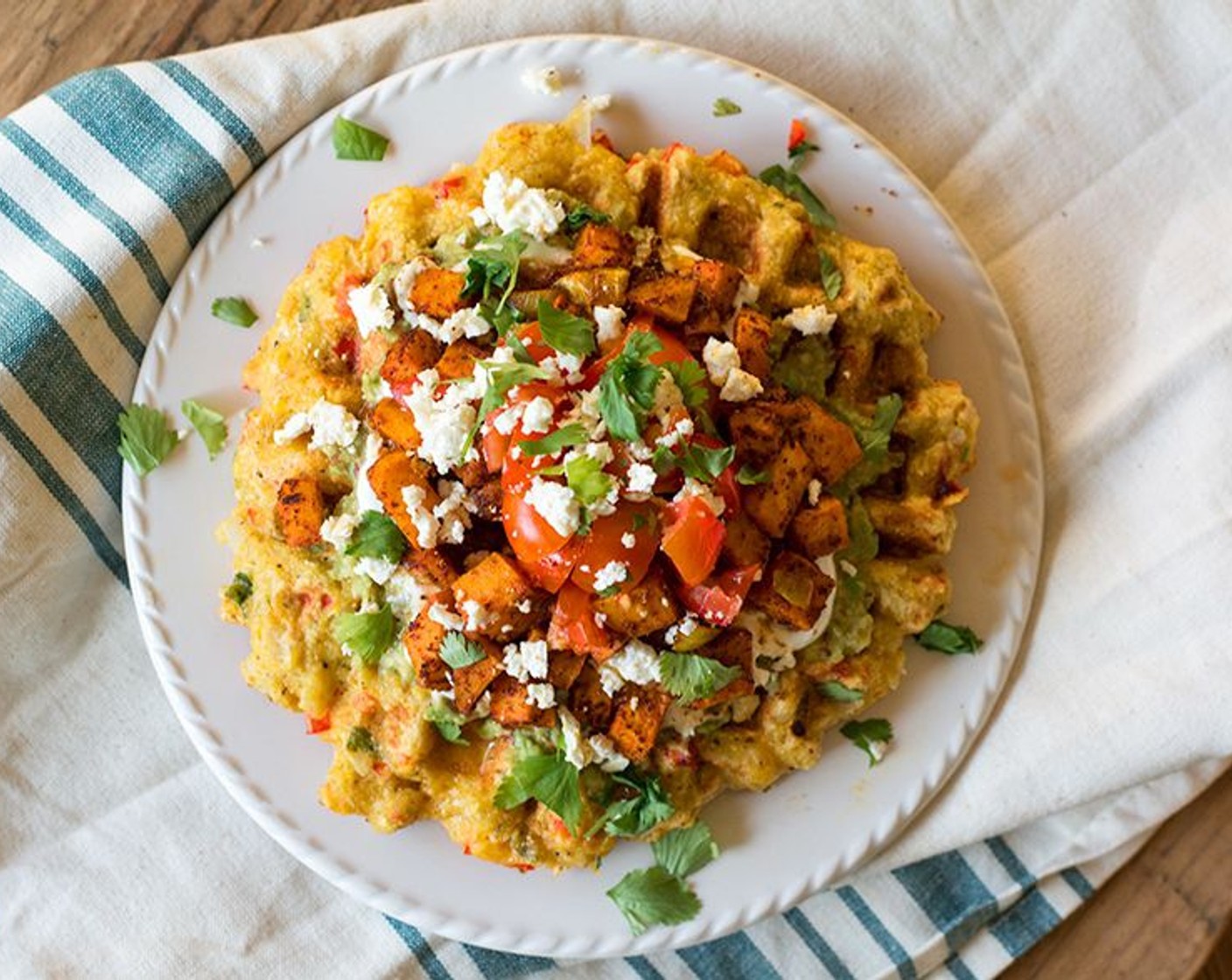 Schritt 13 Die gerösteten Süsskartoffeln zusammen mit den Zwiebeln über die Salsa geben, dann mit Cherrytomaten (4), Feta (3 Esslöffel) und Koriander (2 Esslöffel) garnieren.