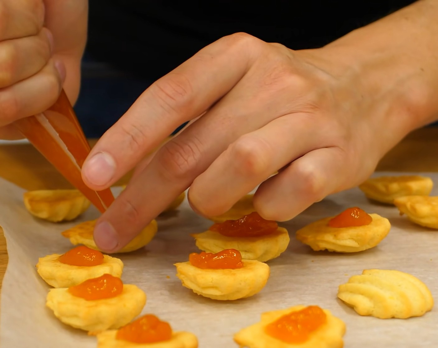 Schritt 10 Anschliessend die Aprikosenkonfitüre (wenig) in einen Spritzbeutel geben und etwas Marmelade auf alle umgekehrten Kekse spritzen.