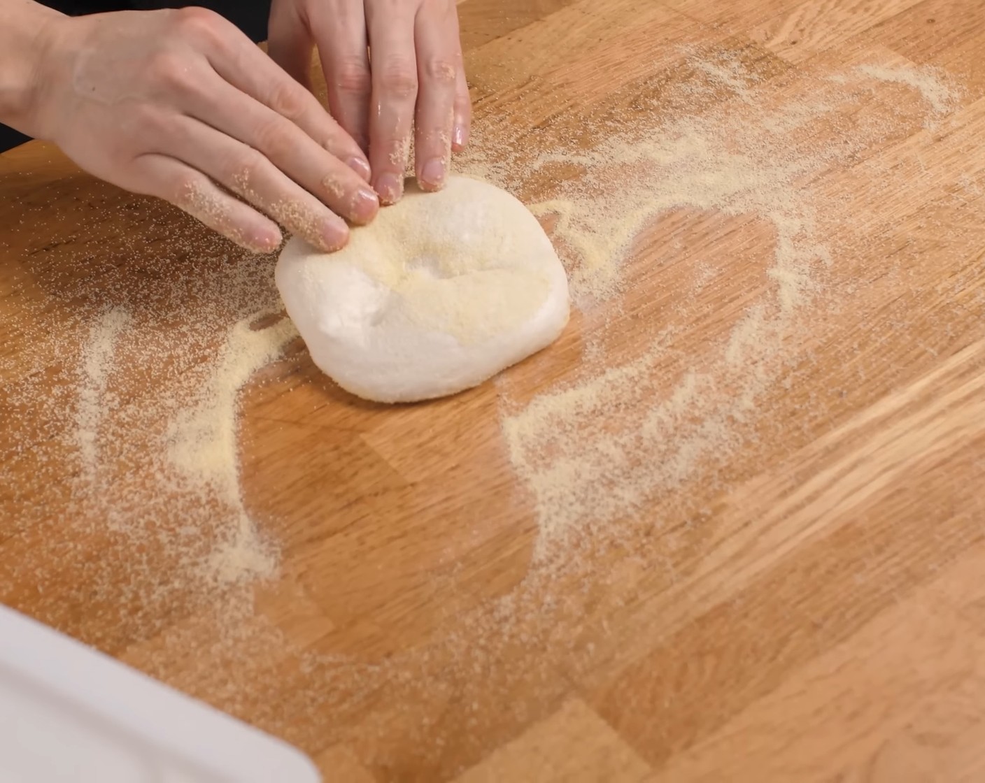 Schritt 13 Nach der Gärzeit die Teiglinge auf etwas Hartweizenmehl (wenig) flach drücken und dann durch sanften Druck das Teigstück ringsum zu einem Kreis auseinander drücken.