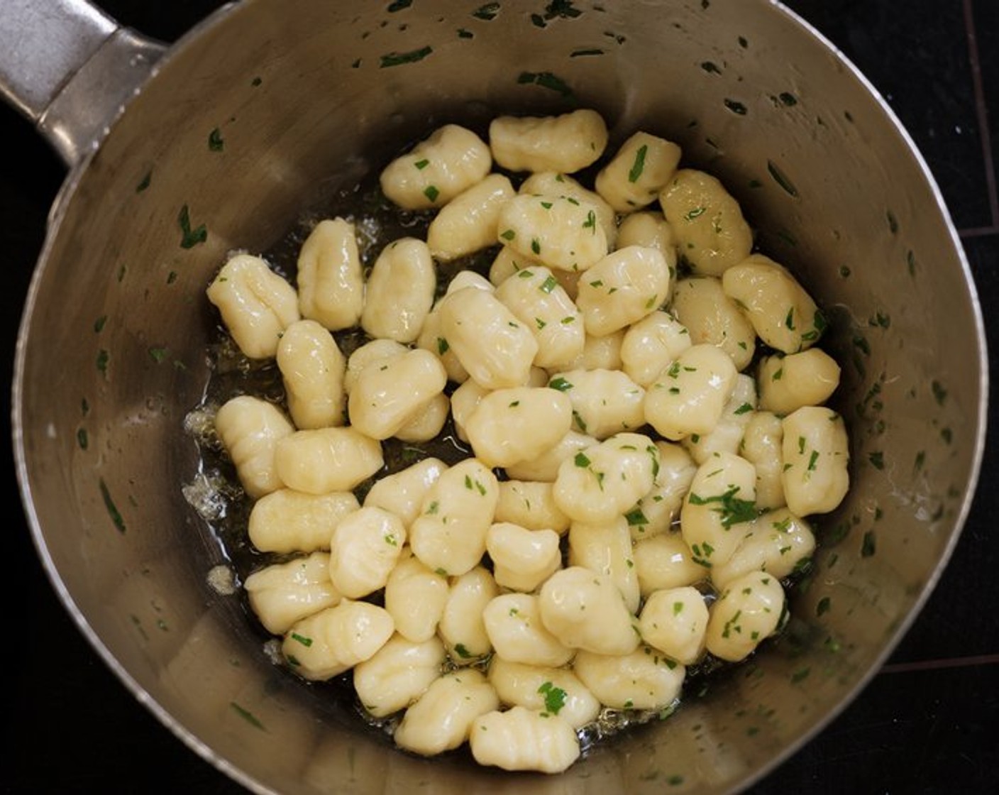 Schritt 2 Die Kartoffeln (500 g) 1 Stunde bei 150 °C im Ofen backen, leicht auskühlen lassen und schälen. Anschliessend passieren und mit den Eiern (4 Teelöffel) und Mehl (170 g) vermischen. Mit Salz (wenig), Pfeffer (wenig) und Muskat (wenig) abschmecken. Die Masse zu Stangen Formen und ca. 3 g schwere Gnocchi abstechen und über eine Gabel rollen. Kurz blanchieren und im kalten Wasser abschrecken. Mit Butter (4 Teelöffel) gleichmässig in einer Pfanne anbraten.