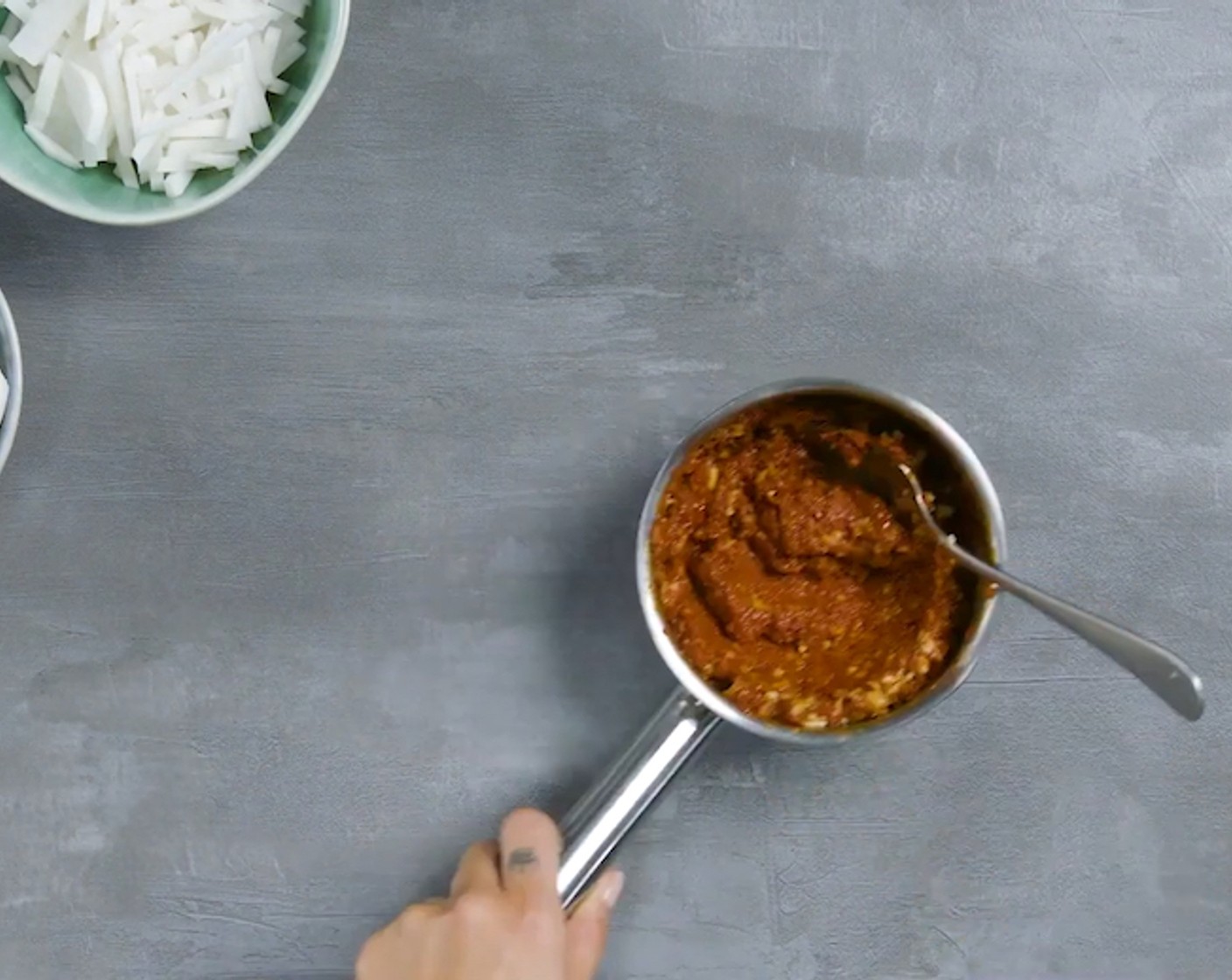 Schritt 2 Inzwischen für die Würzpaste Wasser (175 ml) mit Reismehl (1 EL) in einer kleinen Pfanne verrühren. Mischung unter gelegentlichem Rühren langsam aufkochen, bis die Flüssigkeit bindet. Pfanne vom Herd ziehen, auskühlen lassen. Flüssigkeit mit dem Gochugaru (70 g) mischen und ca. 20 Minuten ziehen lassen.