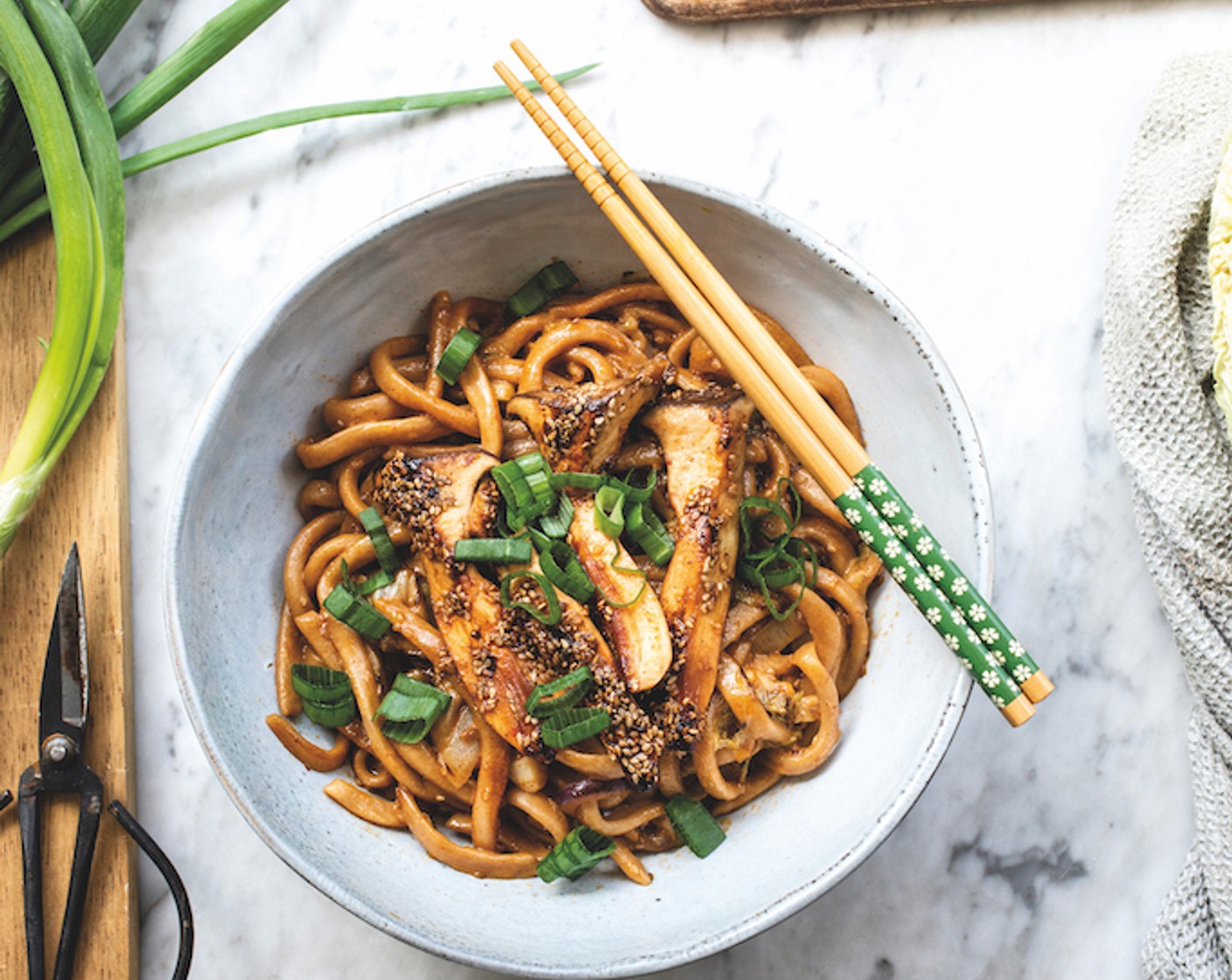 Schritt 5 Die gekochten Nudeln in die Bratpfanne geben und 3 Minuten mitbraten – immer wieder wenden, damit sie nicht anbrennen. Kokosmilch (2 Esslöffel), Sesamöl (1 EL) und nach Belieben noch mehr Sriracha- und Sojasauce oder Salz (wenig) dazugeben. Mit dem geschnittenen Grün der Frühlingszwiebel (nach Bedarf) servieren.