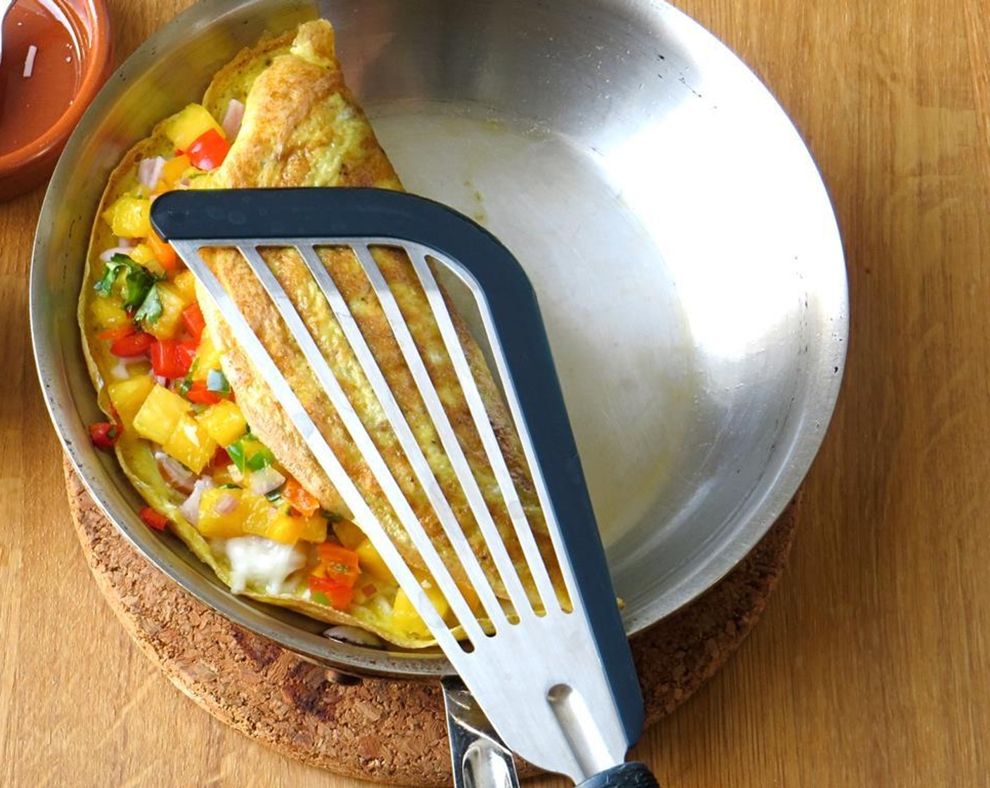 Schritt 9 Mit einem Spatel das Omelett vorsichtig umklappen und leicht andrücken. Etwa 30 Sekunden weitergaren und dabei die Oberseite des Omeletts festhalten.