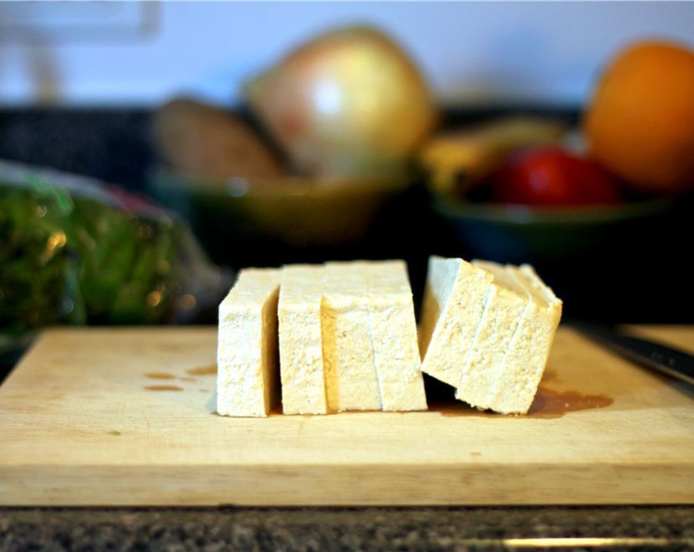 Schritt 2 Tofu (1/2 Pck.) in 4 gleichmässige Scheiben schneiden. Die Scheiben zwischen mehrere Lagen Küchenpapier legen und andrücken, um die Flüssigkeit aufzusaugen.