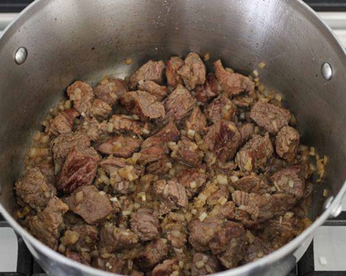 Schritt 3 Gehackte Zwiebel (1) zum Fleisch hinzugeben, mit Salz (wenig) und Pfeffer (wenig) würzen. Zugedeckt bei mittlerer Hitze kochen, bis alles gut durchgegart ist.