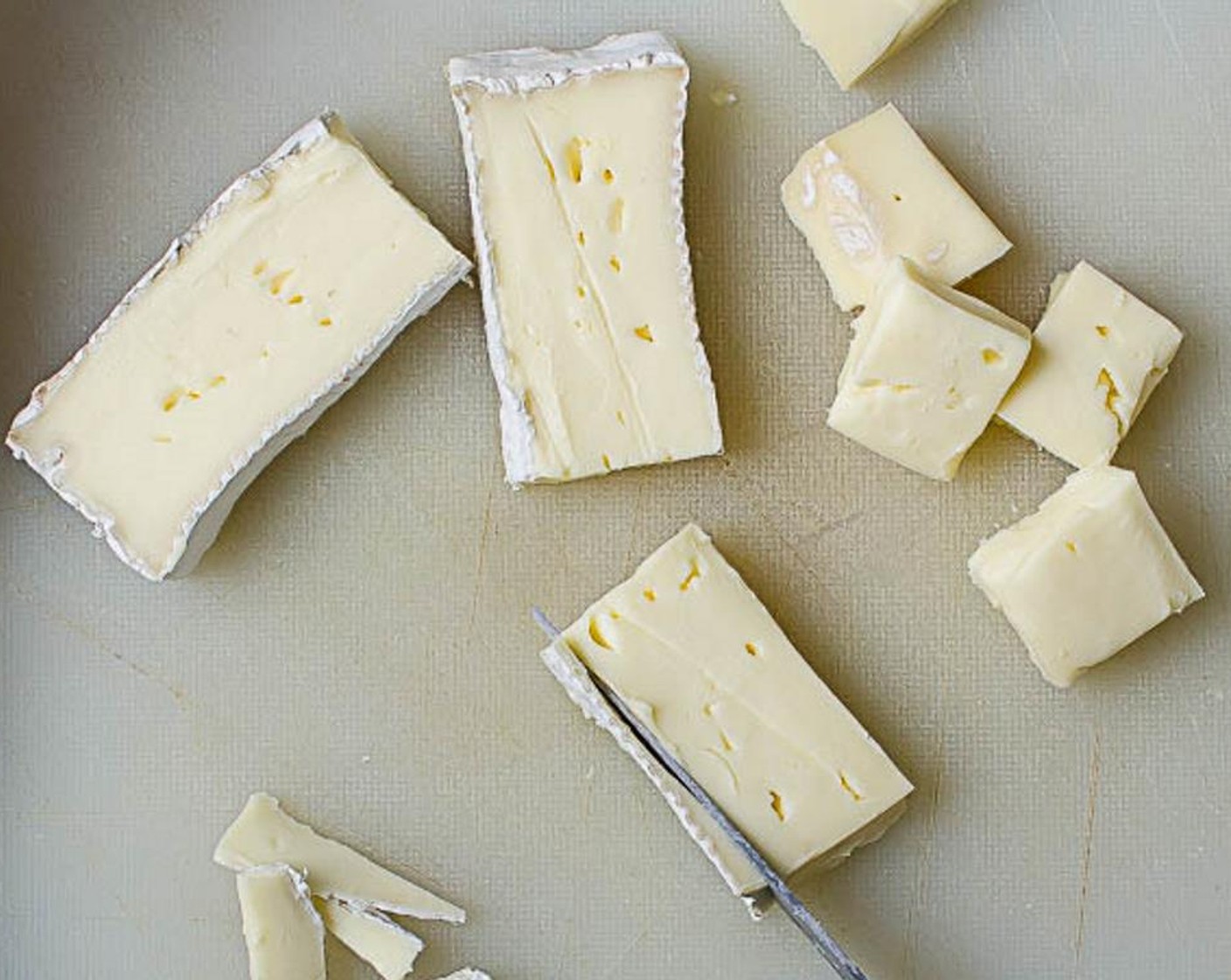 Schritt 5 Die Rinde vom Brie (1/4) abschneiden und den Käse in 2,5 Zentimeter grosse Würfel schneiden. Die Brie-Würfel in Parmaschinken (5 Scheiben) einwickeln und beiseitestellen.