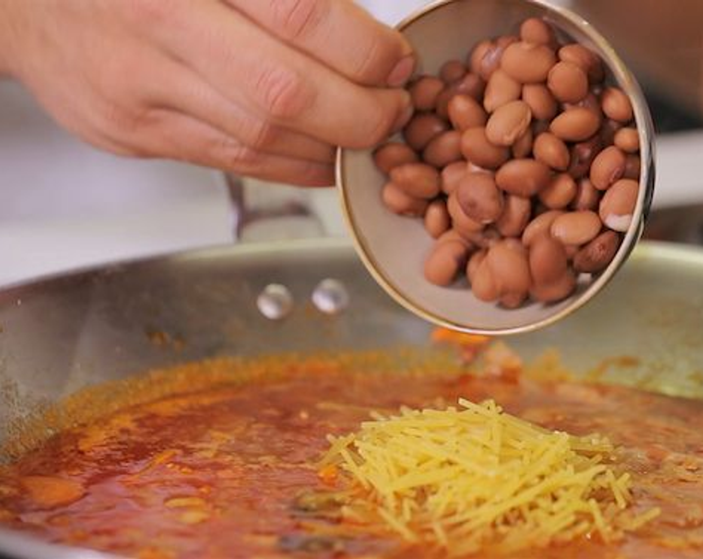 Schritt 5 In der Zwischenzeit, die Spaghetti (80 g) brechen und zusammen mit der Zucchini und den Borlotti-Bohnen (100 g) in den Wok geben. Die Suppe nochmals aufkochen lassen und danach die Hitze reduzieren. Das Ganze simmern lassen, bis die Spaghetti al dente sind. Den Bund Petersilie zum Schluss entfernen.