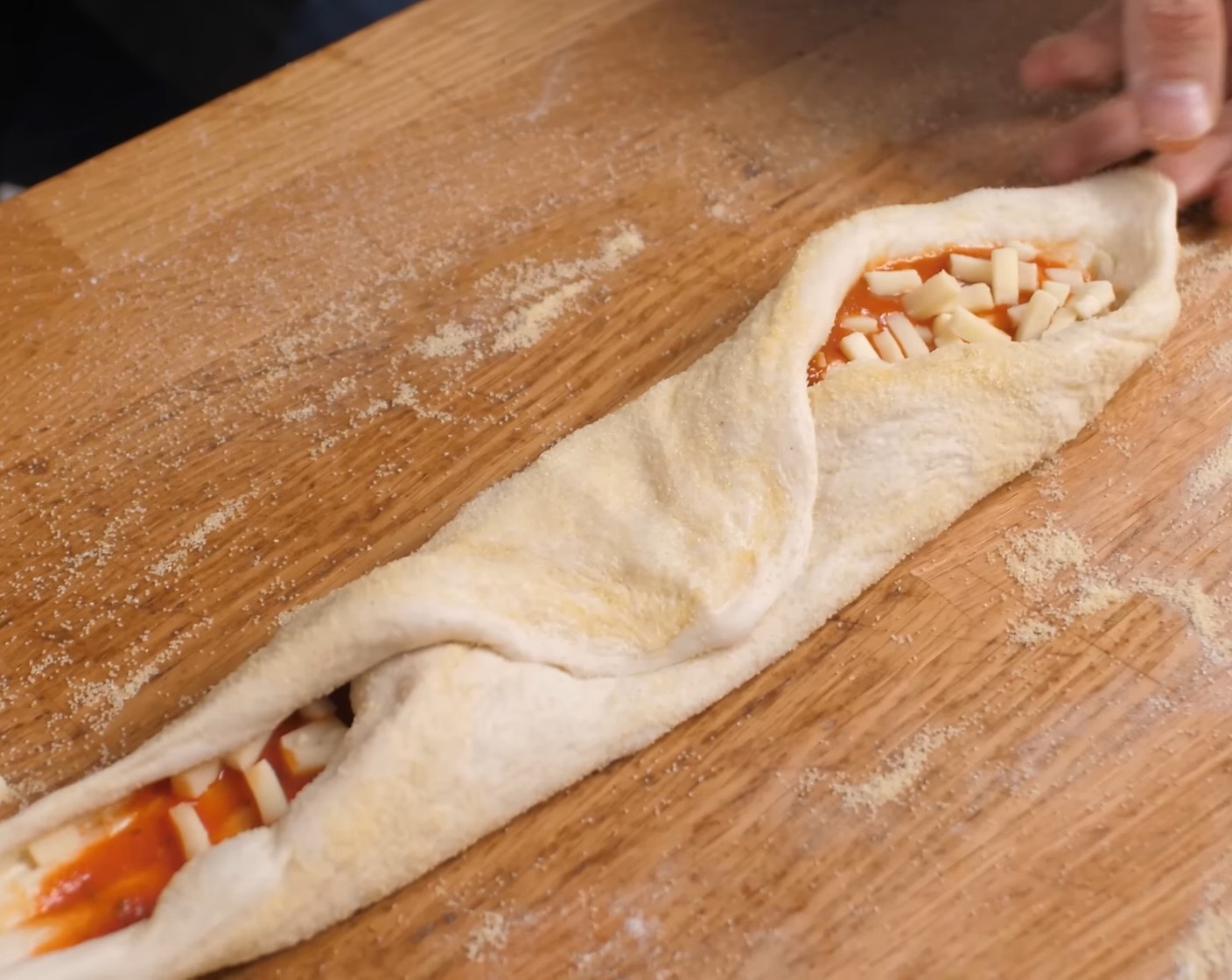 Schritt 16 Dann etwas Mozzarella (wenig) darauf streuen und mittig von der der Längsseite das Teigstück von unten nach oben ziehen, andrücken und so verschliessen.