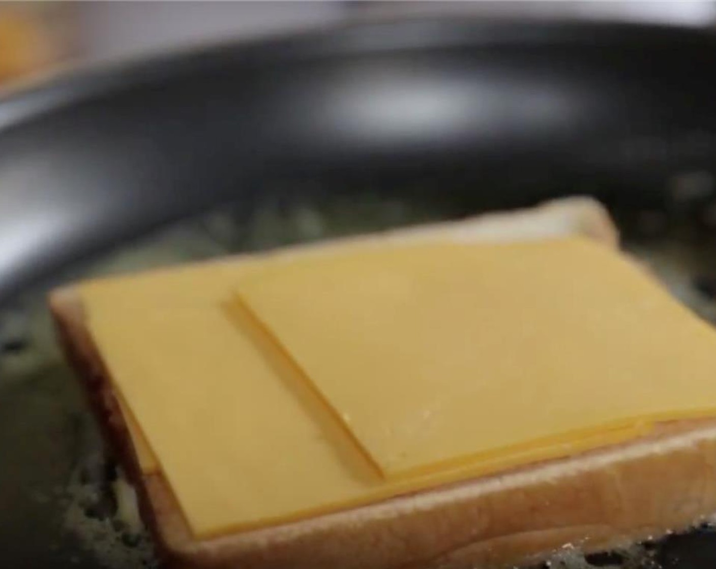 Schritt 3 Wenn die Butter geschmolzen ist, 1 Scheibe Brot mit der Mayonnaise-Seite nach unten in die Pfanne legen. Mit Käse (4 Scheiben) belegen und mit Pfeffer (wenig) würzen.