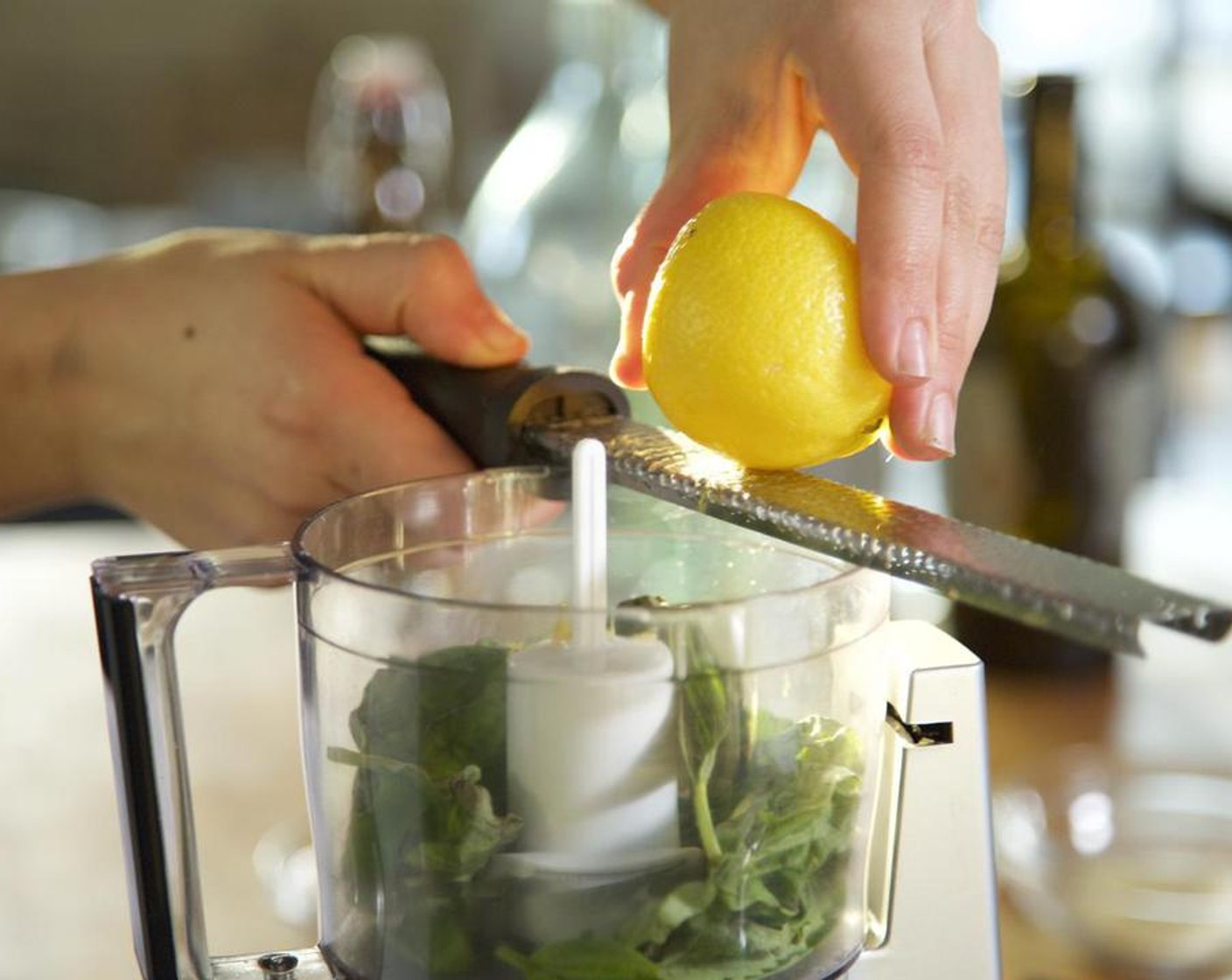 Schritt 2 Die Hälfte der Zitrone (1) direkt in die Küchenmaschine raspeln. Den Saft der Zitronenhälfte in eine kleine Schüssel geben und die Kerne mit einer Gabel entfernen. Den Zitronensaft in die Küchenmaschine hinzugiessen.