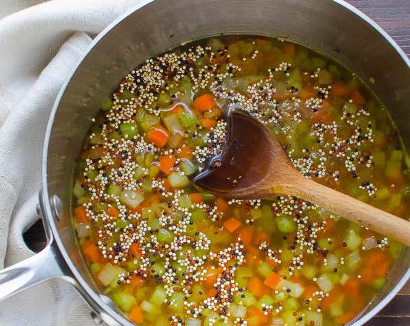 Schritt 3 Während die Linsen kochen, Olivenöl (1 EL) in einem mittelgrossen Topf bei mittlerer Hitze heiss werden lassen. Gemüse und Zwiebeln in die Pfanne geben. Kurz anbraten, bis die Zwiebeln glasig sind. Quinoa (125 g) und Wasser (360 ml) hinzufügen und zum Kochen bringen.
