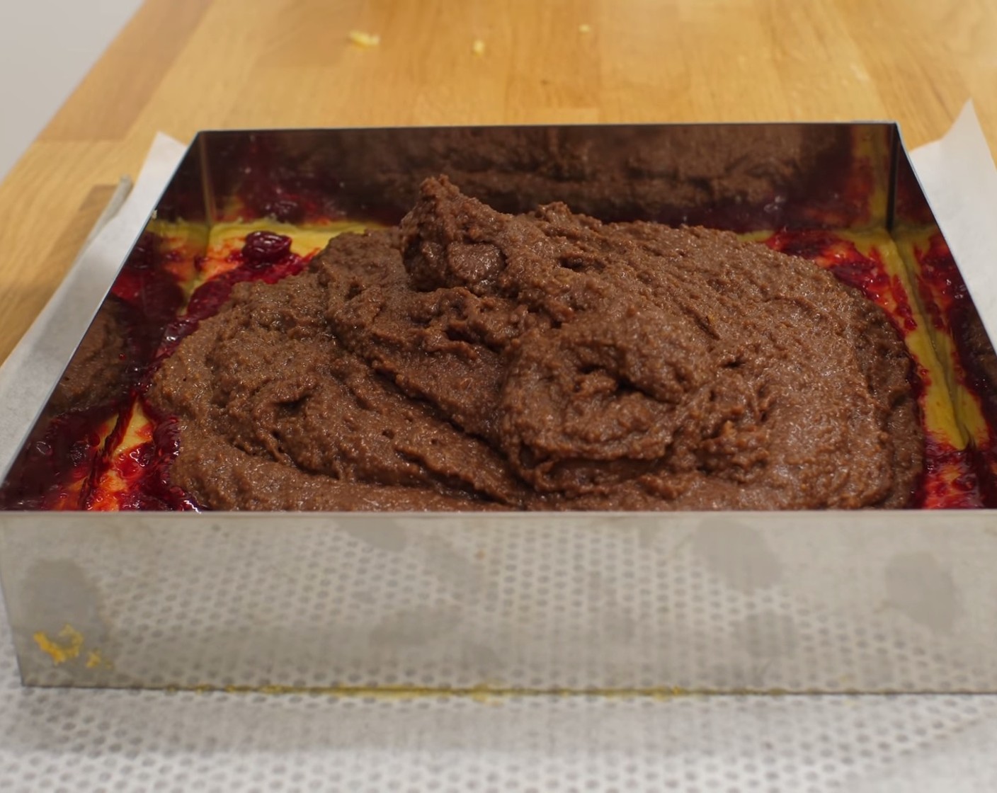 Schritt 10 Den Teigboden gleichmässig mit Himbeerkonfitüre (120 g) bestreichen, die Kuchenmasse einfüllen und gleichmässig verteilen.