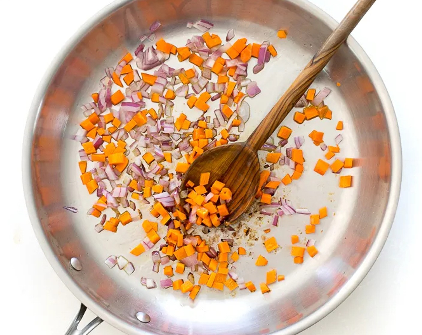 Schritt 2 Sonnenblumenöl (2 Esslöffel) in eine mittelgrosse Pfanne geben und bei mittlerer Hitze erhitzen. Karotten (75 g) und Zwiebeln (75 g) hinzugeben und für etwa 3-4 Minuten garen.